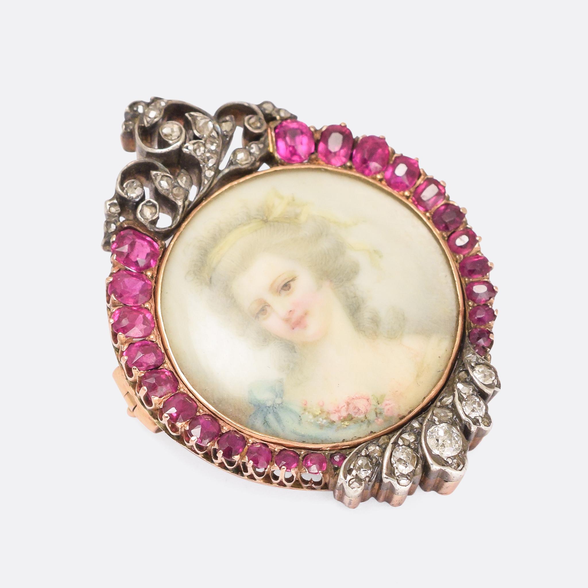 A glorious Victorian miniature portrait brooch dating from the latter half of the 19th Century, circa 1880. The lady depicted wears a yellow ribbon in her hair, and a light blue dress adorned with pink roses. The frame is quite spectacular, set with