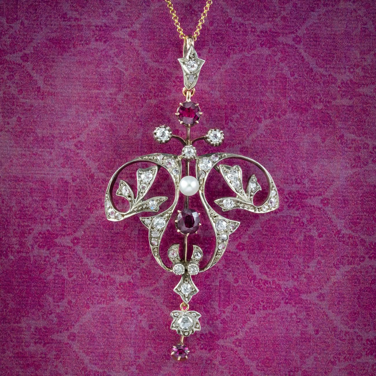 A stunning antique Victorian Art Nouveau pendant from the late 1800s decorated with an array of twinkling old cut diamonds (approx. 1ct) three cherry-pink rubies (approx. 0.90ct) and a central pearl.

Ruby is the birthstone of July and has long been