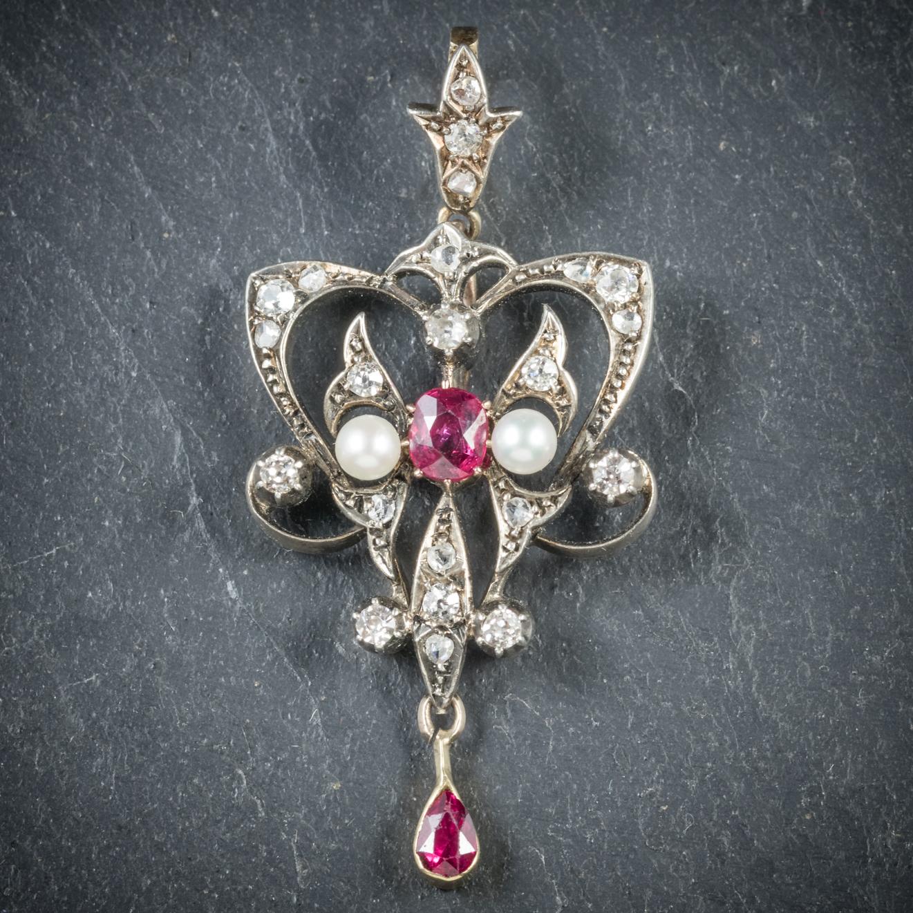 This beautiful antique Ruby and Diamond pendant is from the Victorian era, Circa 1900

The lovely pendant is adorned with a 0.10ct Ruby dropper with a rich pink 0.25ct Ruby in the centre flanked by two lustrous Pearls

The gallery is set in Platinum
