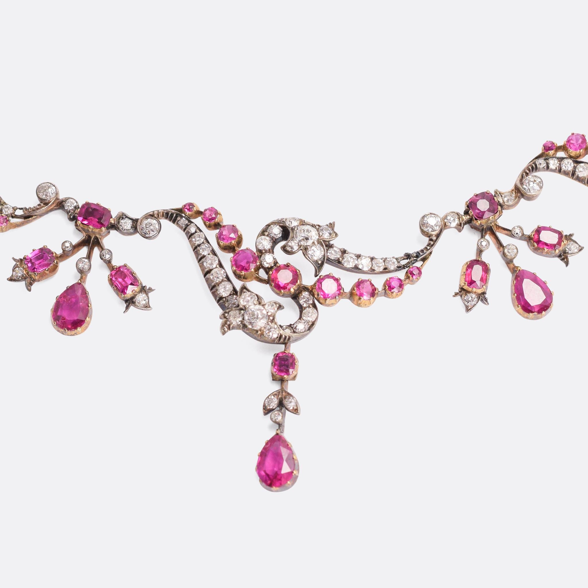 A breathtaking Victorian ruby and diamond necklace in the Rococo Revival style. The design is full of character and life with asymmetrical, organic swirling motifs - the silver settings home to vibrant ruby drops and over three carats of old mine