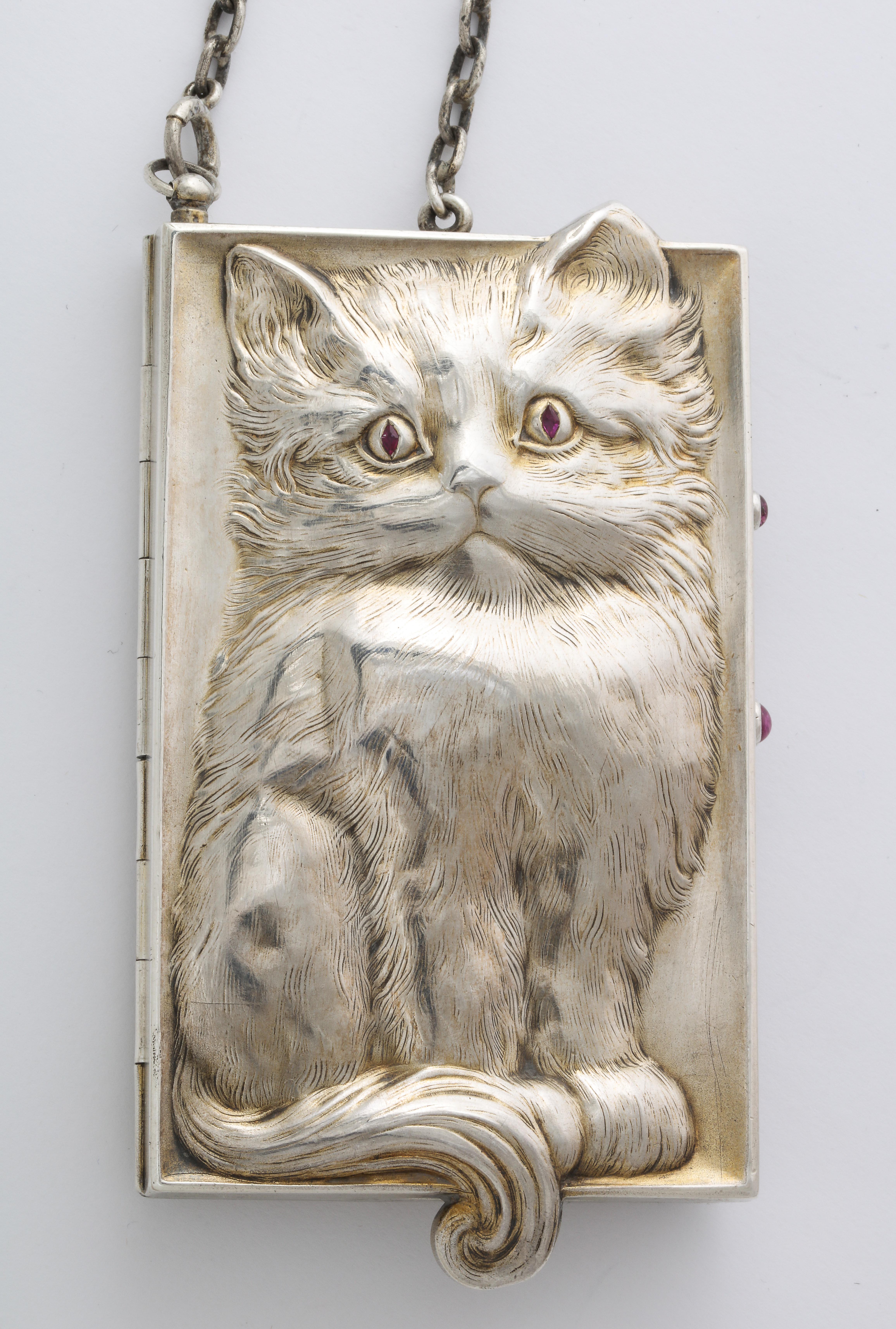 Detail and amusing nuance will endear this sterling silver compact to the hearts of cat lovers. Engraved so that the cat rises from the silver background, the front side shows the entire animal with its ruby eyes catching yours. Turn to the back and