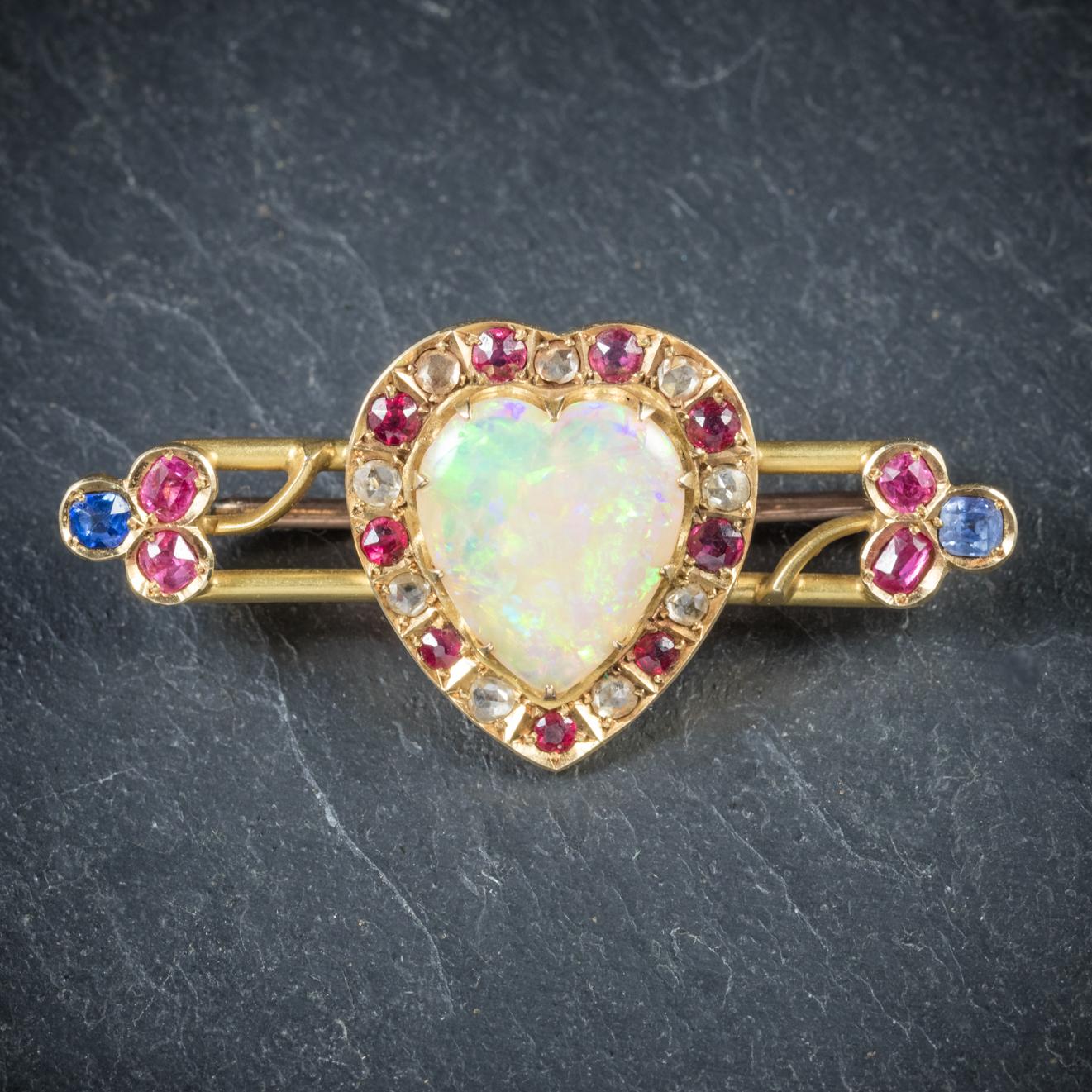 This beautiful antique Gemstone heart brooch is Victorian Circa 1900

The brooch is adorned with a pretty 6ct heart shaped Opal in the centre and surrounded by Rubies and Diamonds

The brooch stems out and leads to two small shamrocks at each end