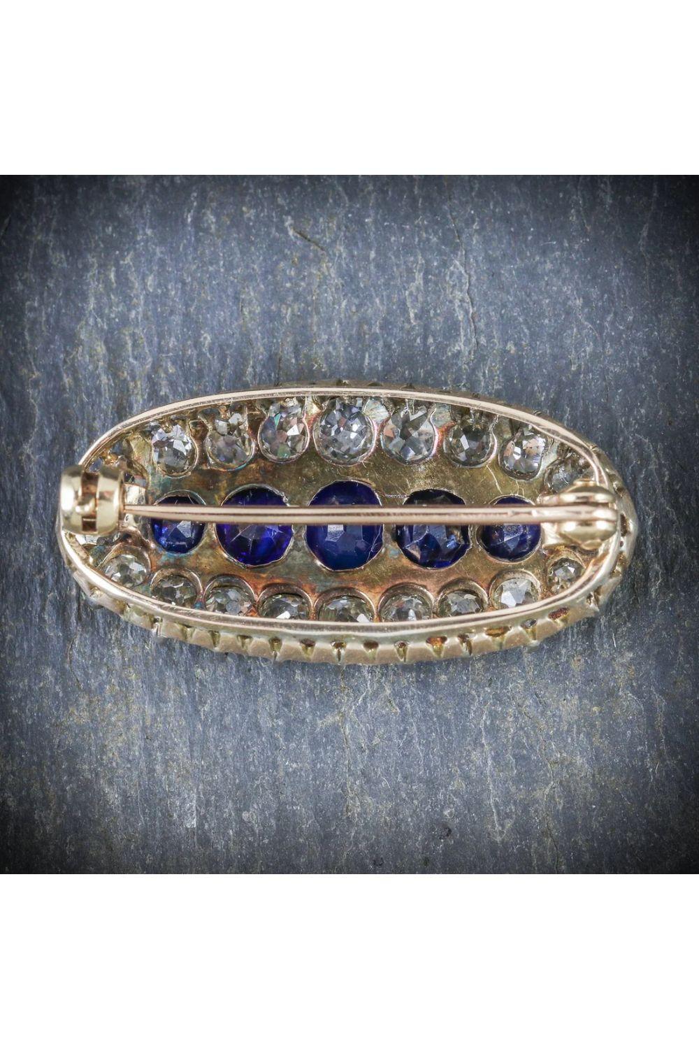 Eine atemberaubende antike viktorianische Brosche mit fünf tiefblauen Saphiren in der Mitte, umrahmt von einem Rahmen aus zwanzig funkelnden Diamanten im Minenschliff. Die Saphire haben eine Größe von 0,20 bis 0,50 ct (insgesamt ca. 1,5 ct) und die