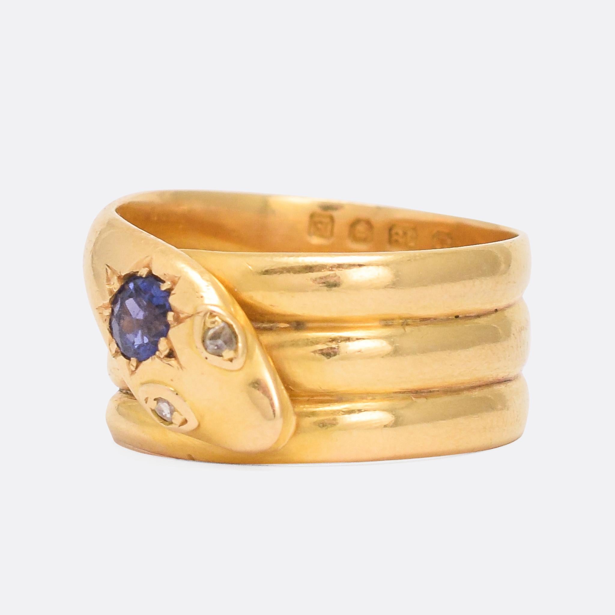 A superb Victorian coiled snake ring set with a vibrant natural sapphire on its head, and rose cut diamonds for eyes. It's finely worked, modelled in 18 karat gold with a friendly caricatured face. Clear London hallmarks date it to the year 1880. A