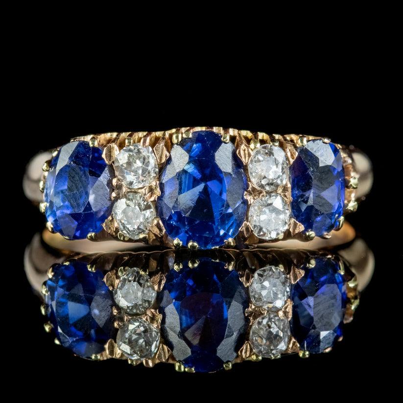 A stunning antique late Victorian ring modelled in 18ct gold and claw set with a trilogy of deep blue sapphires, with four old mine cut diamonds glistening in between.

The largest sapphire is approx. 0.85ct in the centre, flanked by two 0.55ct