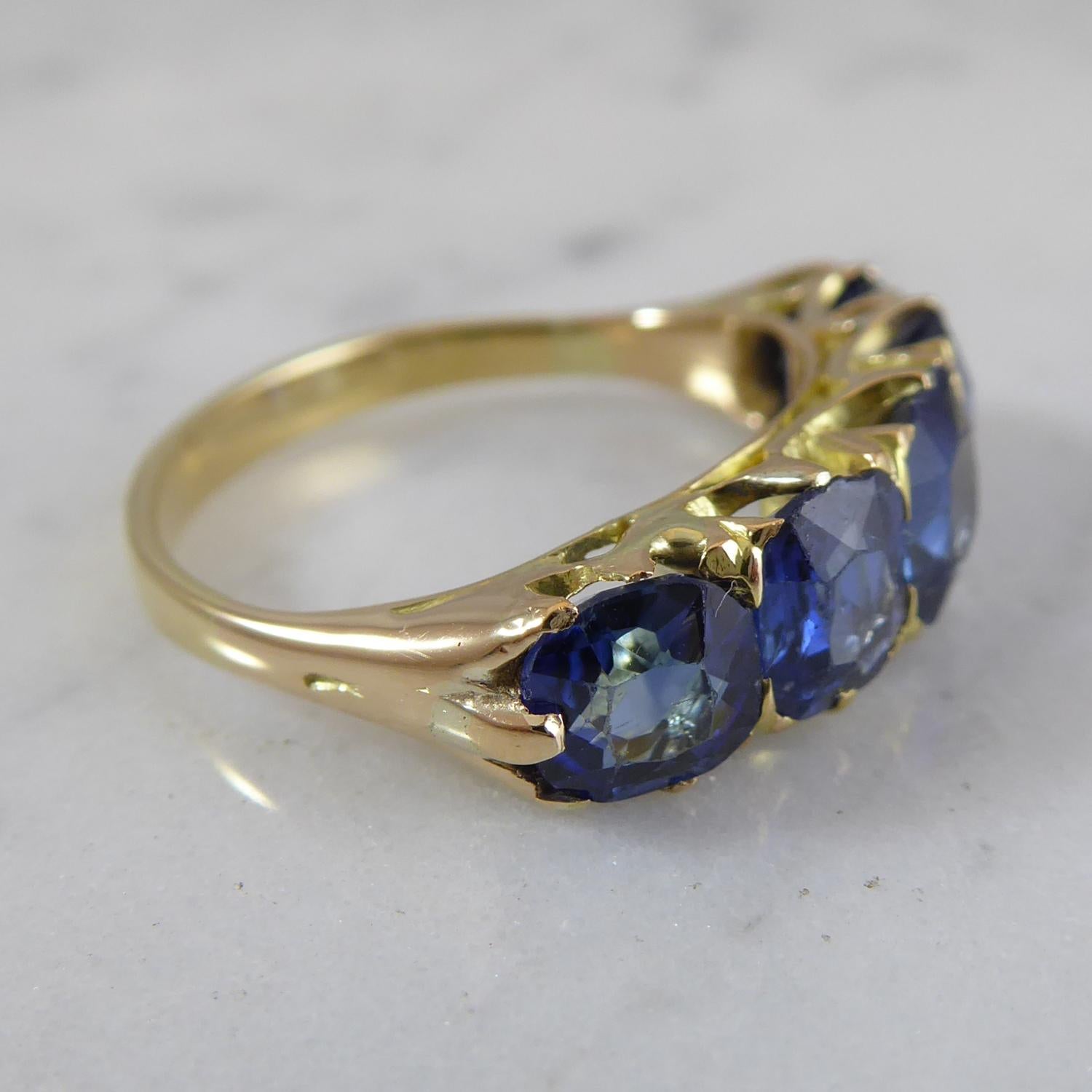 A five stone diamond ring dating from the late Victorian era.  Set with five graduated cushion cut sapphires of good colour in yellow claw settings to a plain polished band.  Not hallmarked.  Finger size 6 (US/Canada), M (UK/Australia) with some