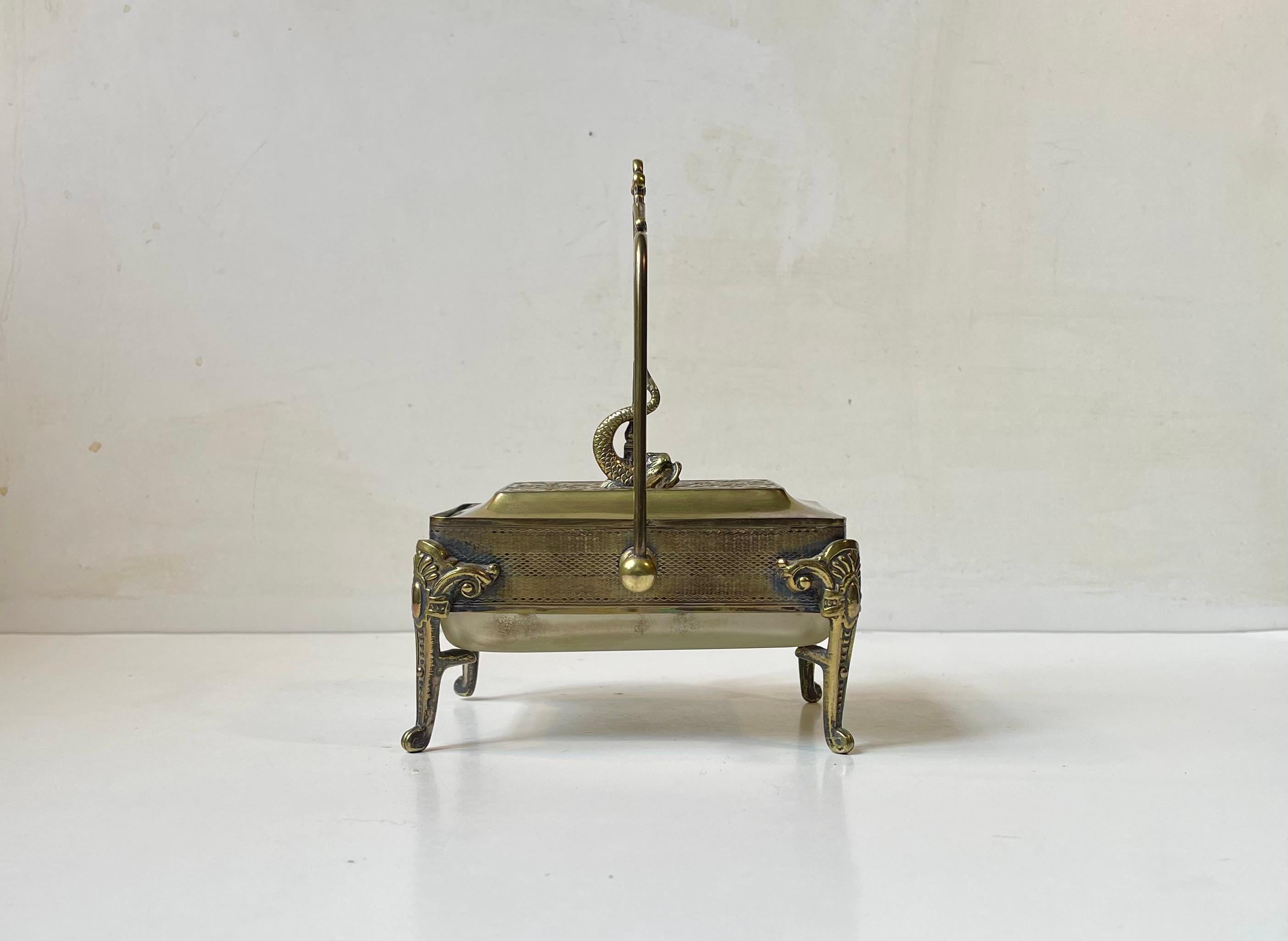 Une belle boîte à sardines exécutée en laiton et verre dépoli et dotée d'une poignée imposante. Détails complexes et savoir-faire artisanal sur l'ensemble de la pièce. Son ancien placage d'argent a été usé. Il présente une patine arc-en-ciel sur les