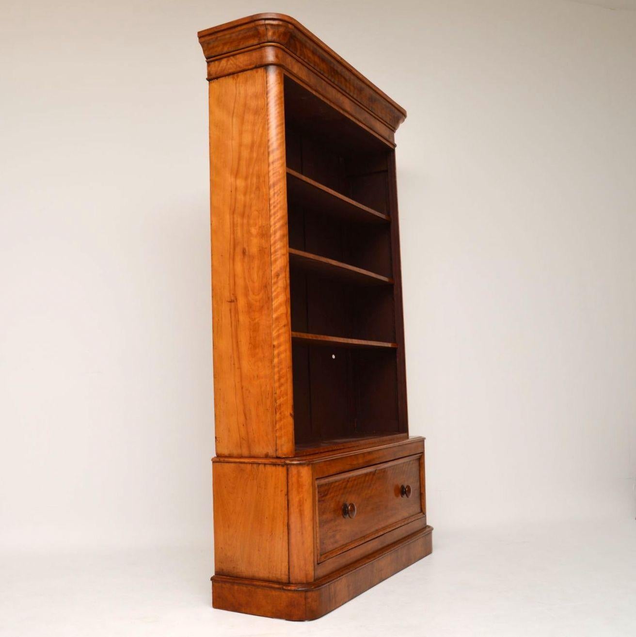 Antique Victorian satinwood open bookcase with adjustable shelves and sitting on a single drawer base section. It’s in very good condition and dates from circa 1860s-1880s period. The corners are curved all the way down from the very pronounced
