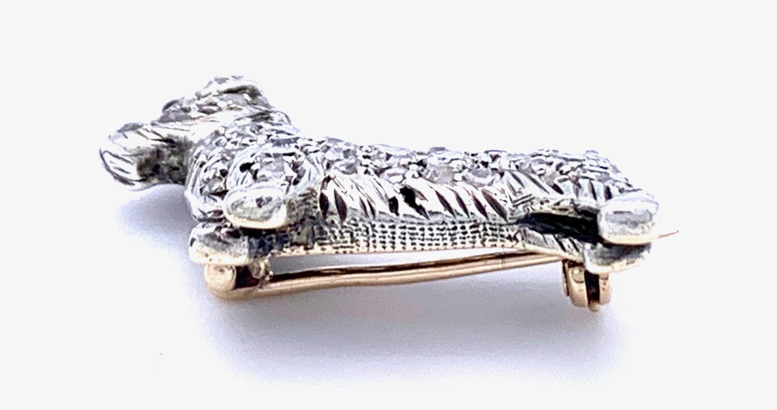 This charming little brooch is in the shape of a puppy scotch terrier. It is set with diamonds, full and rose cuts. His fully modelled head is decorated with two rubies as eyes. The diamonds are mounted in silver on gold. This is a typical example