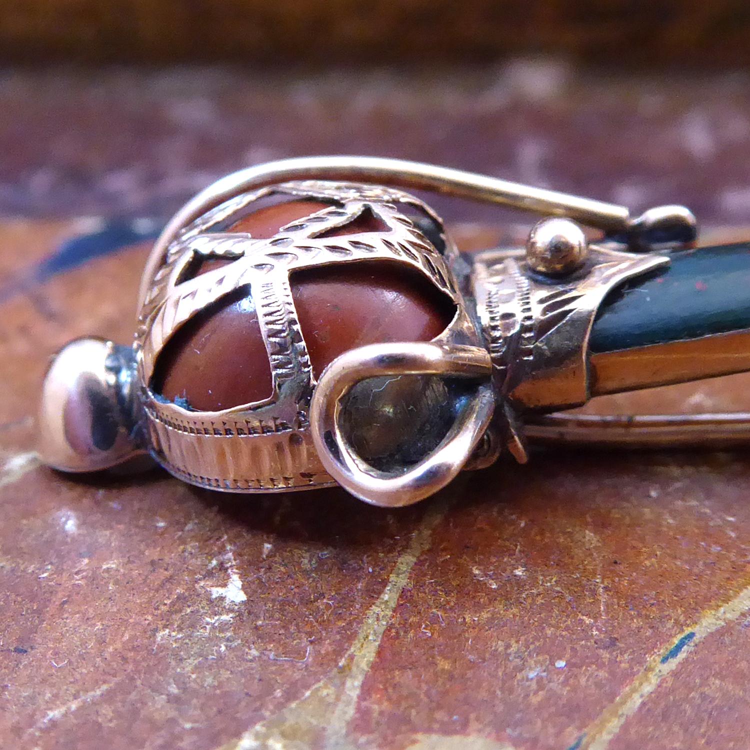 An antique Scottish dagger or sgian-dubh brooch of very nice quality.  Featuring a cornelian orb within a rose gold decorative cage and leading to the dagger comprised of bloodstone to the top half and cornelian to the lower half.  The gemstones