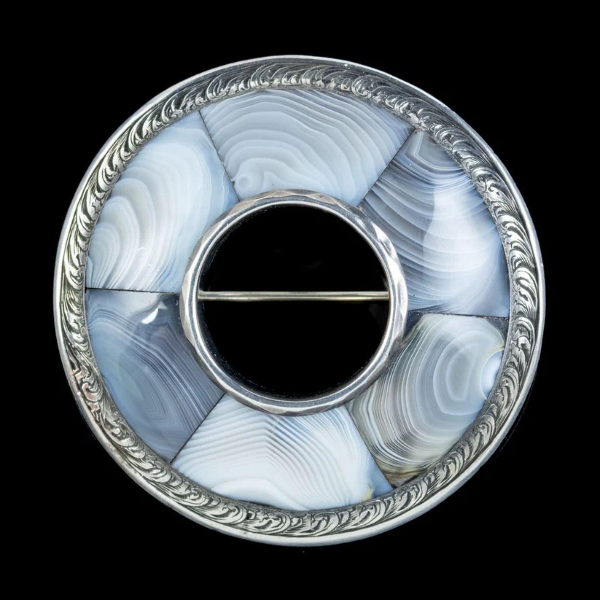 A magnificent Antique Scottish brooch from the mid Victorian era (Circa 1860). The large, domed design is all Silver with a detailed foliate engraved border and six pieces of beautiful Montrose Agate inlaid around the central hole.  

Montrose