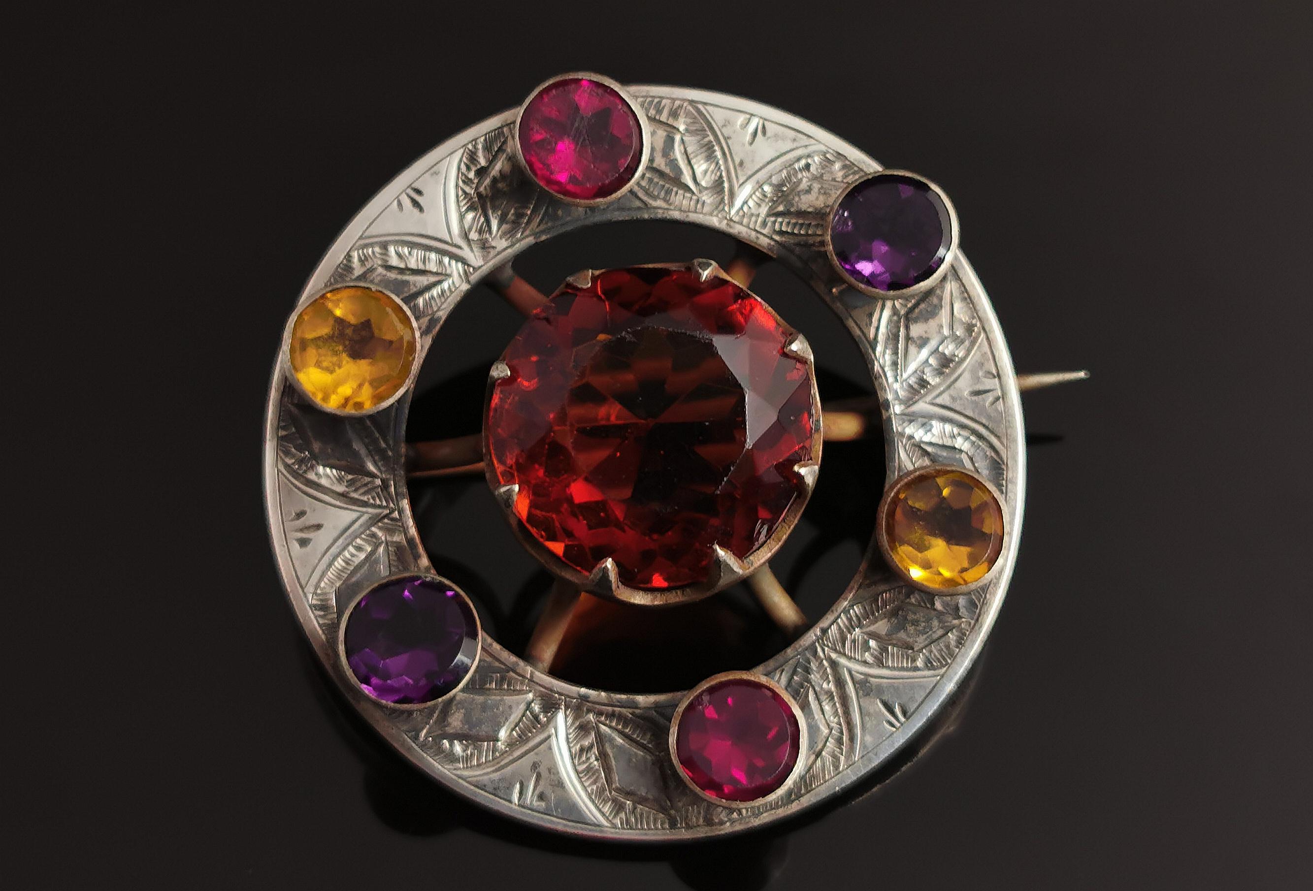 A stunning antique Victorian Scottish silver and paste brooch.

An engraved silver base set with raised colourful paste stones in various bright colours; citrus yellow, Amethyst purple and cerise pink.

The brooch is set to the centre with a large
