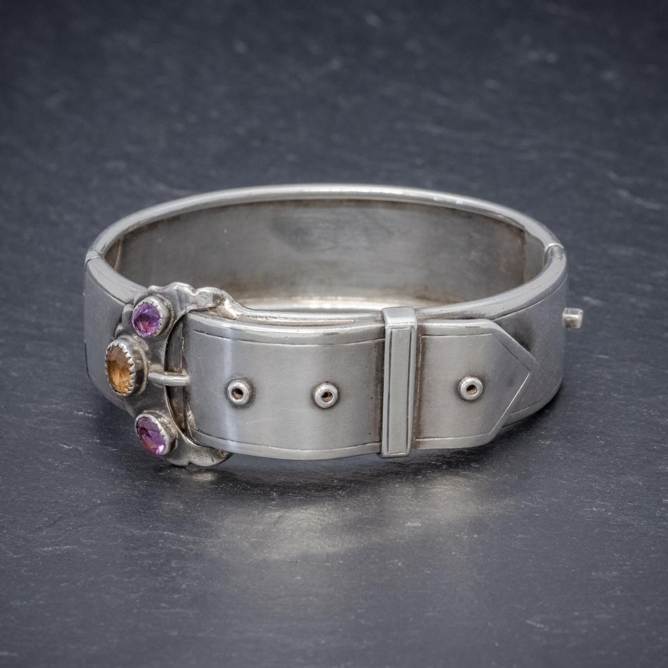 A wonderful antique Victorian Scottish cuff bangle shaped like a large belt with a Citrine and two Amethysts set on top of the buckle.  

The piece is fashioned in Sterling Silver and is solid and substantial. It is a beautiful design and has