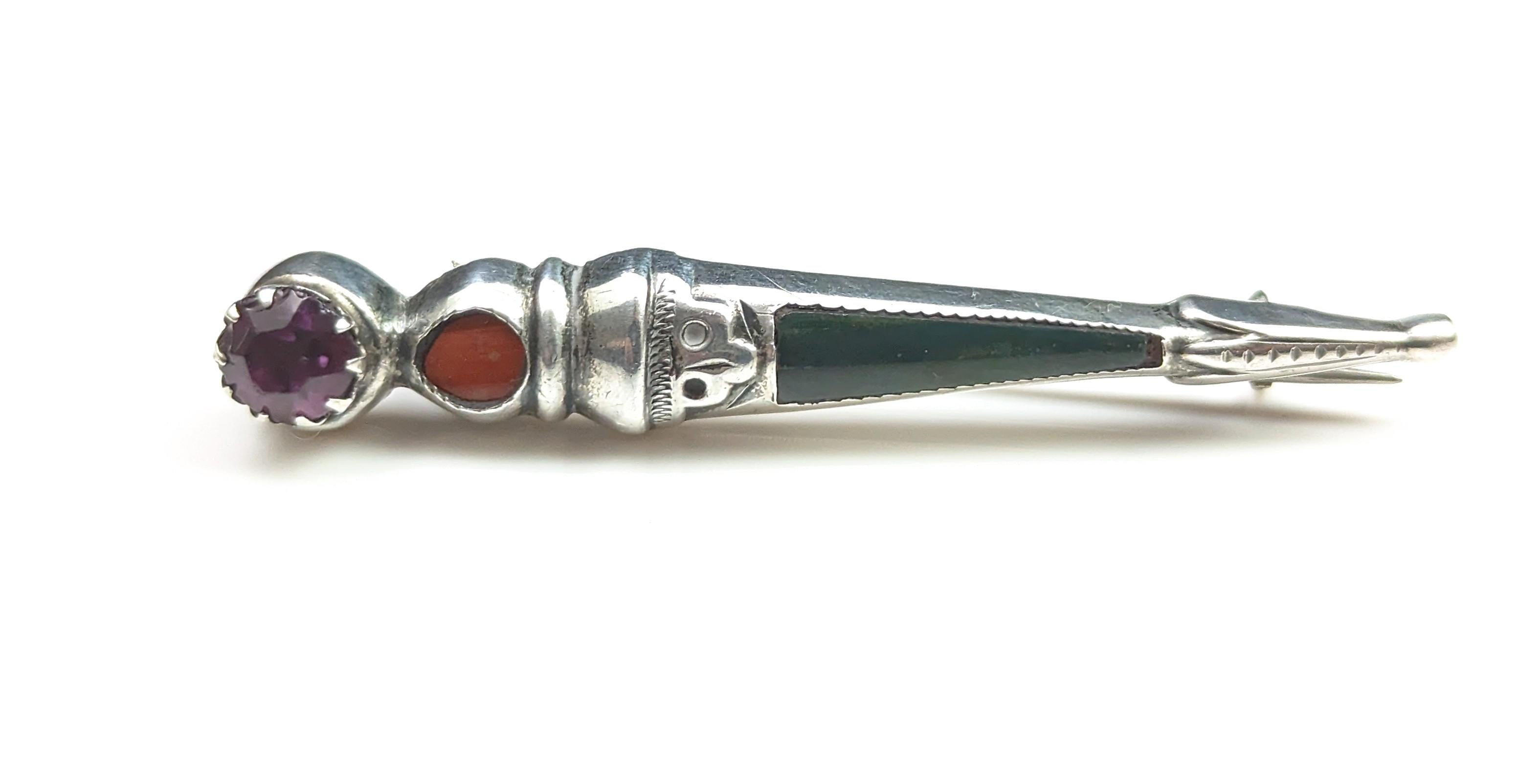 An attractive antique, Scottish agate and Silver Dirk brooch.

It has an amethyst paste stone to the top and a single circular red Jasper just below, the main length of the Dirk is set with dark green Bloodstone.

The brooch is crafted in cool