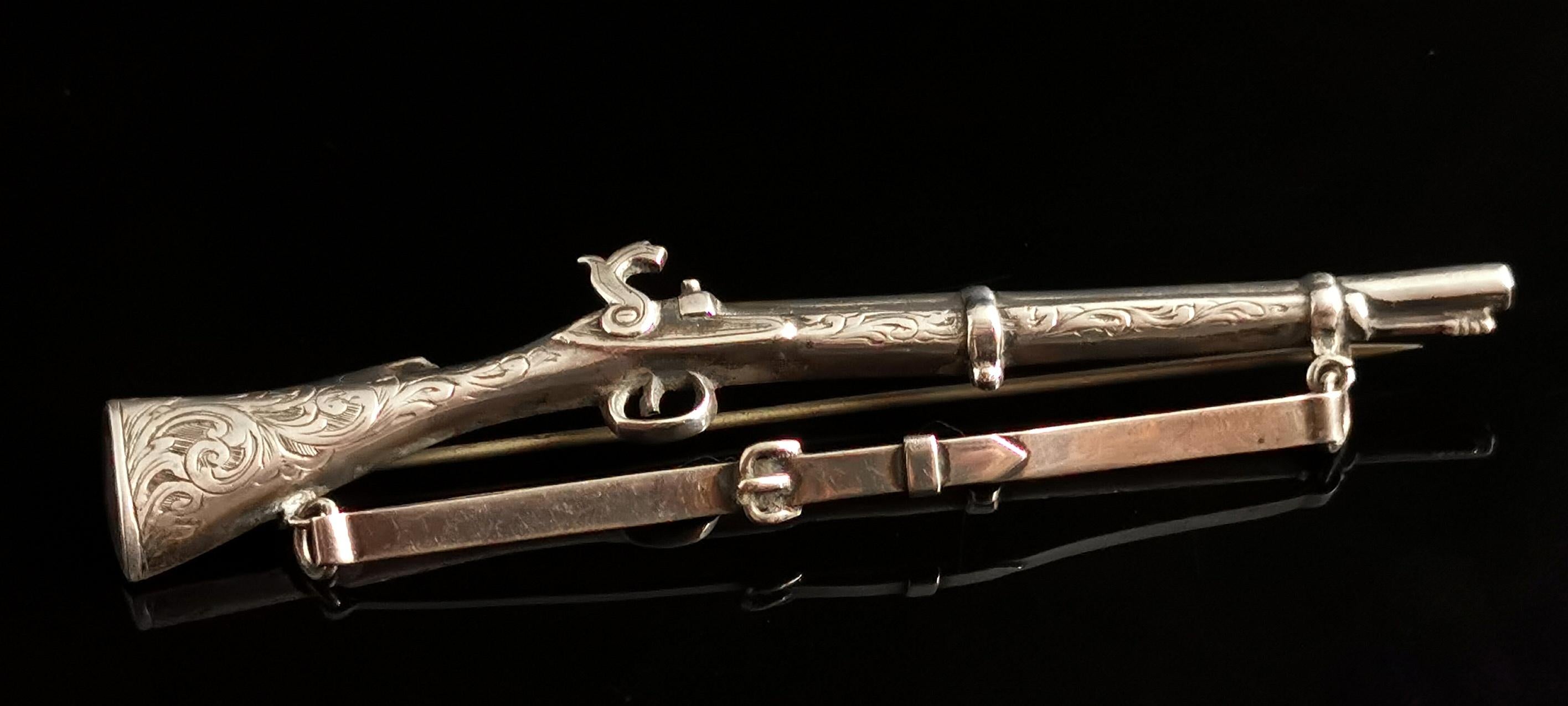 A stunning antique Victorian era Scottish sterling silver musket or rifle brooch.

It is a large and highly detailed piece, the front is engraved with aesthetic style swirls of foliate.

It has an articulated belt strap hung at the bottom of the