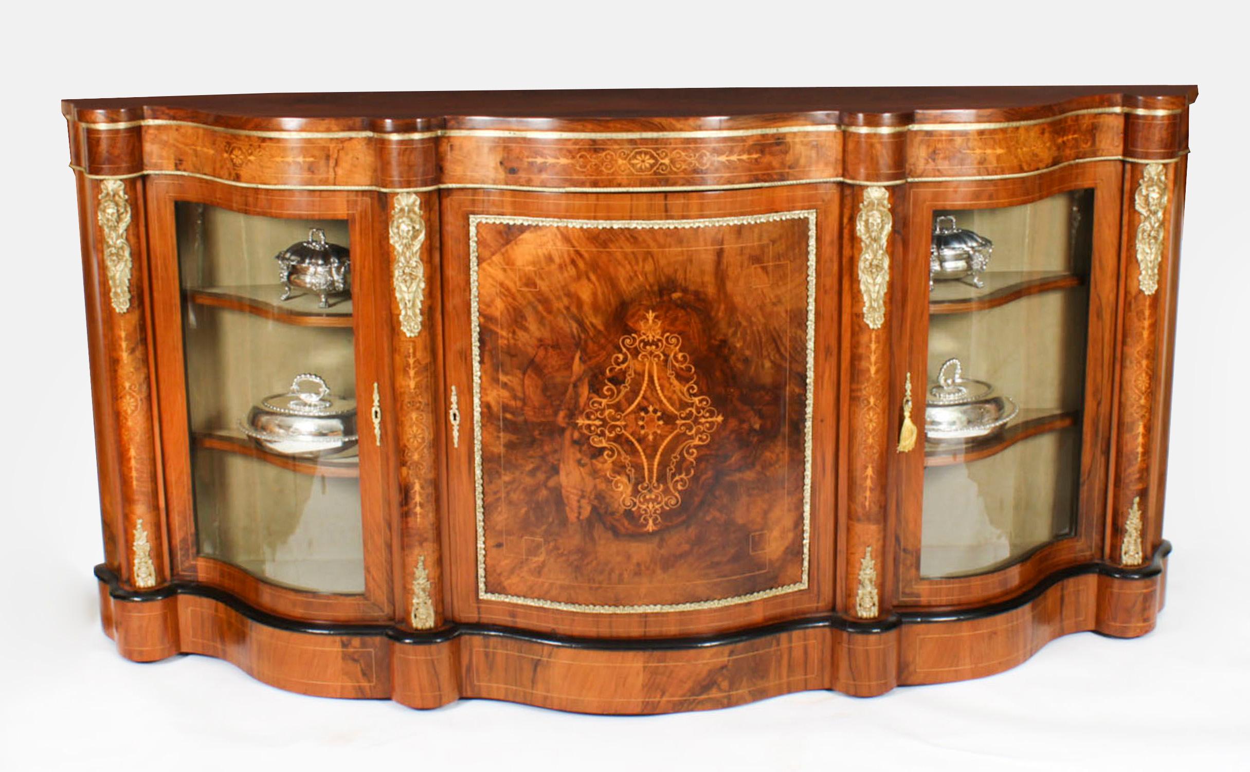 This is an exceptional quality antique Victorian ormolu mounted burr walnut and marquetry inlaid serpentine credenza, circa 1870 in date.
 
The entire piece highlights the unique and truly exceptional pattern of the book matched burr walnut