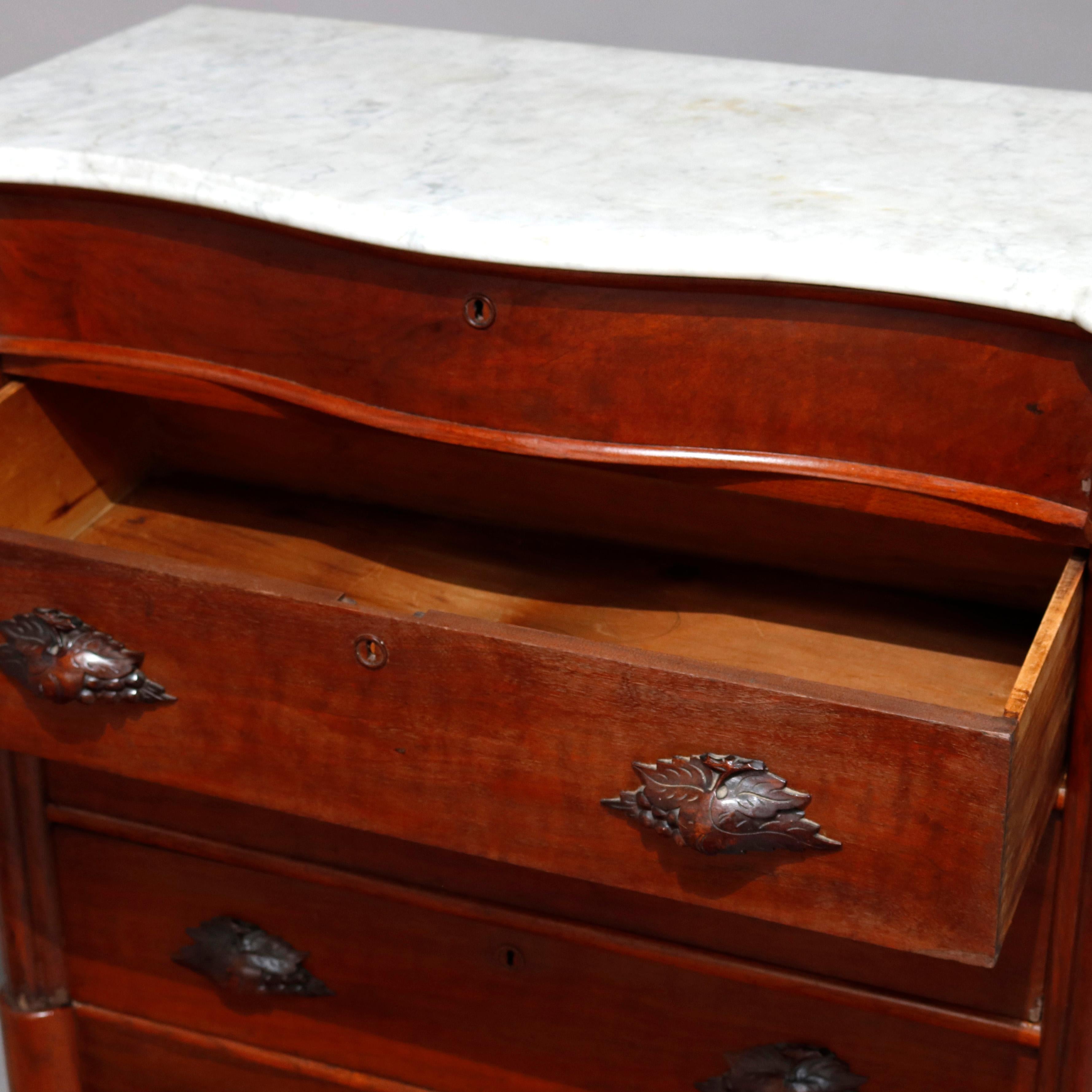 An antique Victorian chest of drawers offers shaped and beveled top surmounting case with serpentine frieze drawer over three long drawers having foliate carved pulls and flanked by cluster column supports, circa 1880

Measures: 37.5