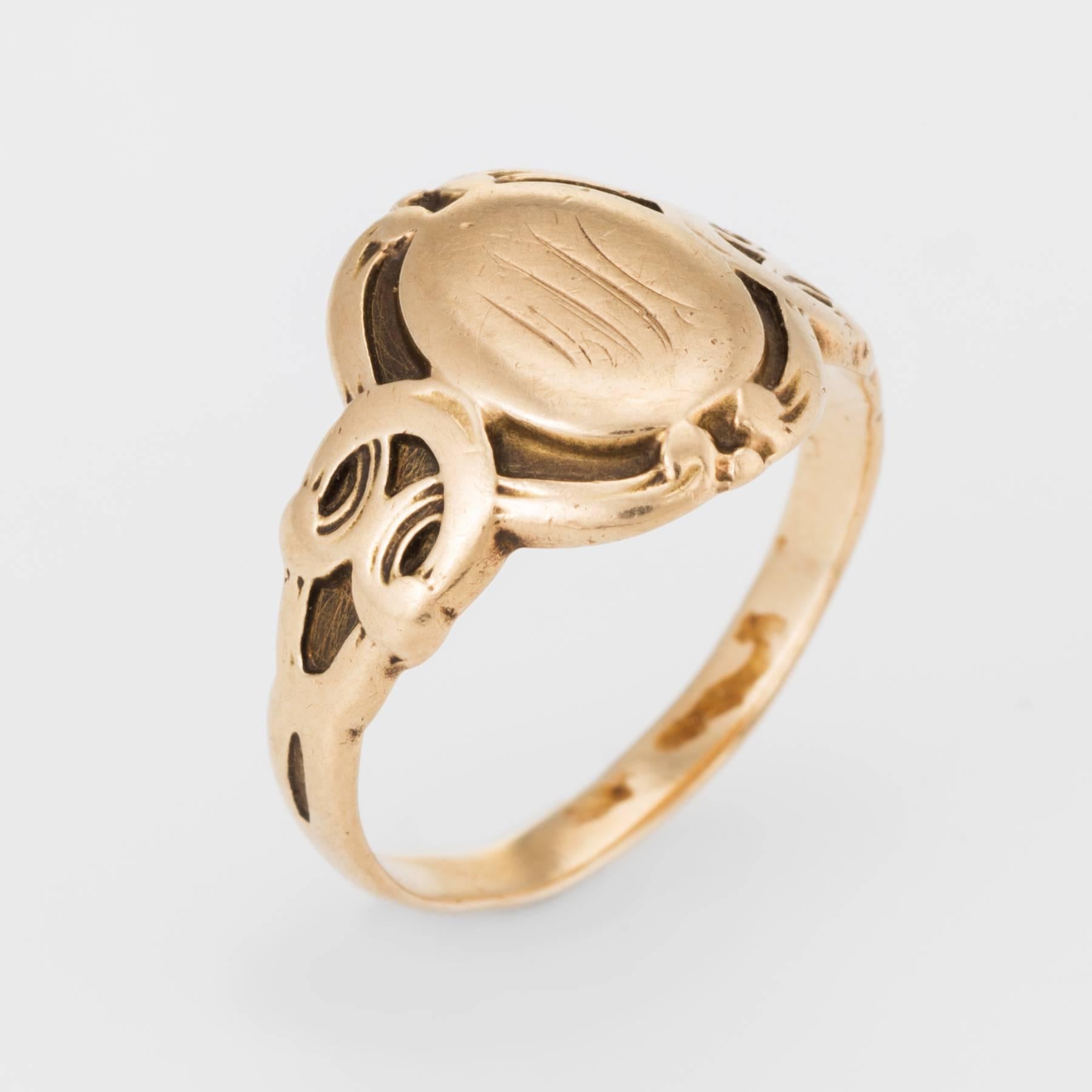 Victorian era signet band (circa 1880s to 1900s), crafted in 14 karat yellow gold.

Charming oval signet features scrolled side shoulder detail. Note: the inscription along with the side shoulders has worn down due to the age of the ring.  

The