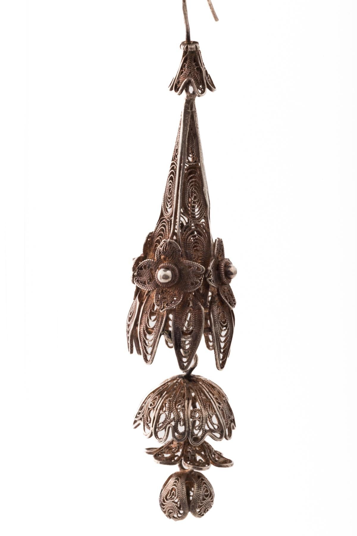 A pair antique filigree earrings that look as if they were woven by an experienced spider. These are hand made of cascading concentric circles and flowers of fine wire and granulation. There are traces of the original gold wash that make parts