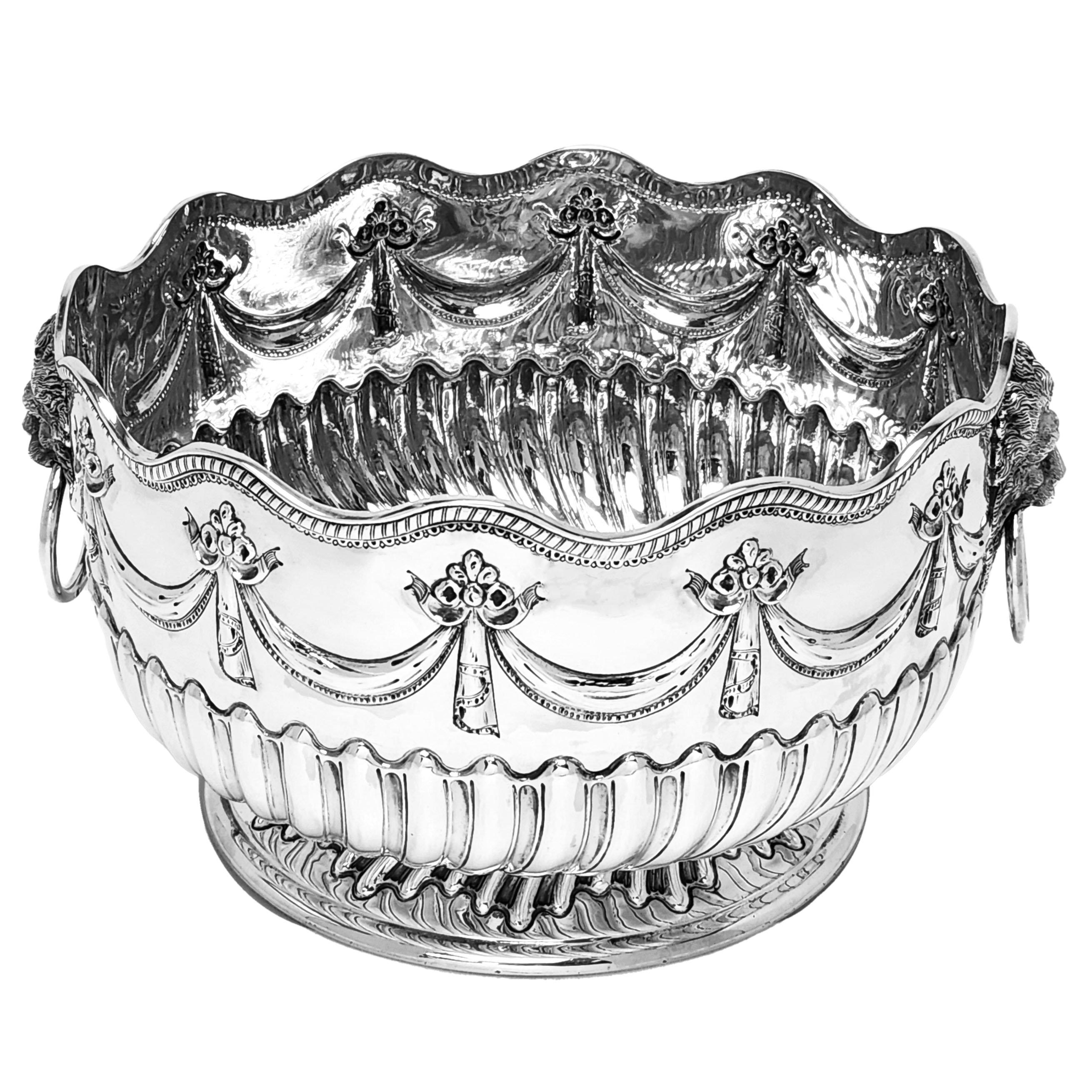 An Antique Victorian Solid Silver Bowl decorated with elegant chased designs. The lower half of the Antique Bowl show a chased writhen fluted design with a swag and floral chased and above this. This Bowl has a pair of impressive Lion Head Ring