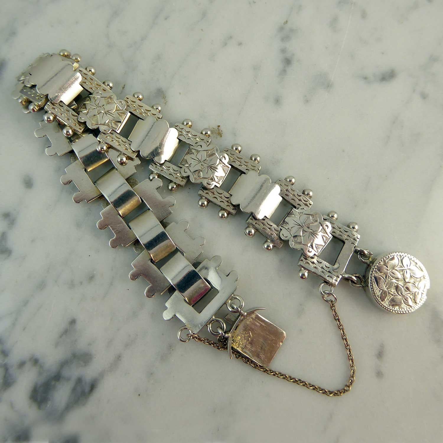 Victorian silver bracelet dating from circa 1899.  The bracelet comprises 13 rectangular silver links with a hand etched pattern and silver bead decoration.  These links are connected by bevelled links with a scalloped edge and alternate between