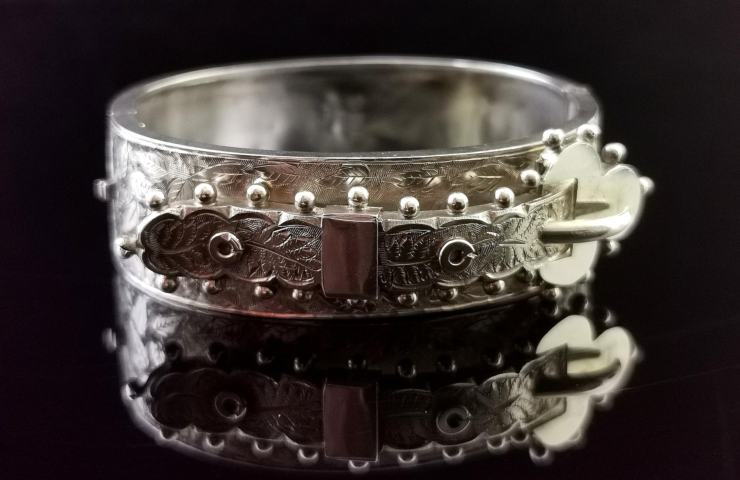 A beautiful antique Victorian era sterling silver buckle bangle.

It has an elaborate buckle design front with a beaded edge and engraved with fern leaves.

The reverse has a smooth polished finish and the bangle has a push clasp.

A beautiful and