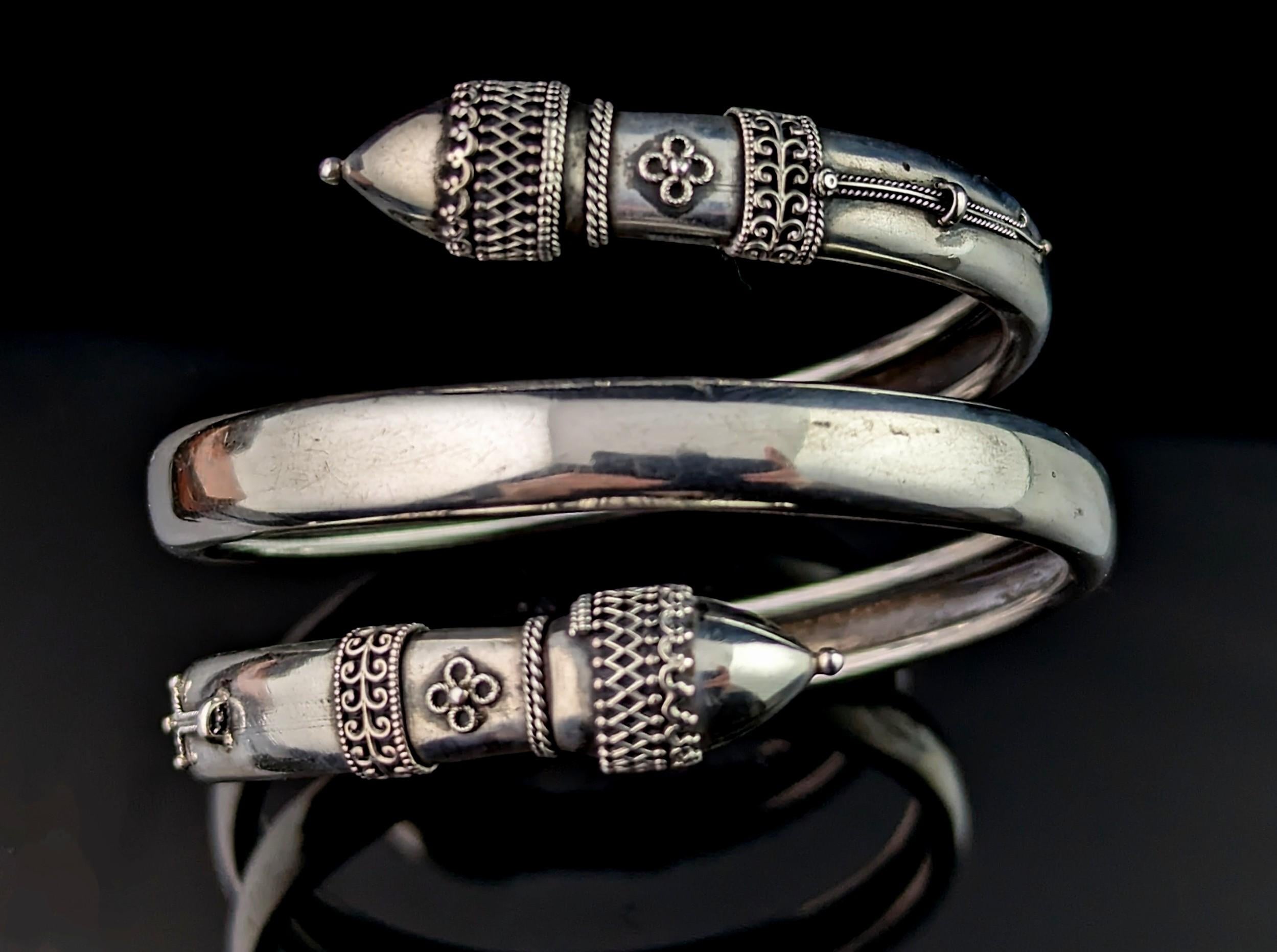 You can't help but be enchanted by this truly beautiful antique Victorian silver bypass bangle.

Designed in the Etruscan revival manner it has decorative finials with applied silver wirework, the bangle wrapping around three times, it has a