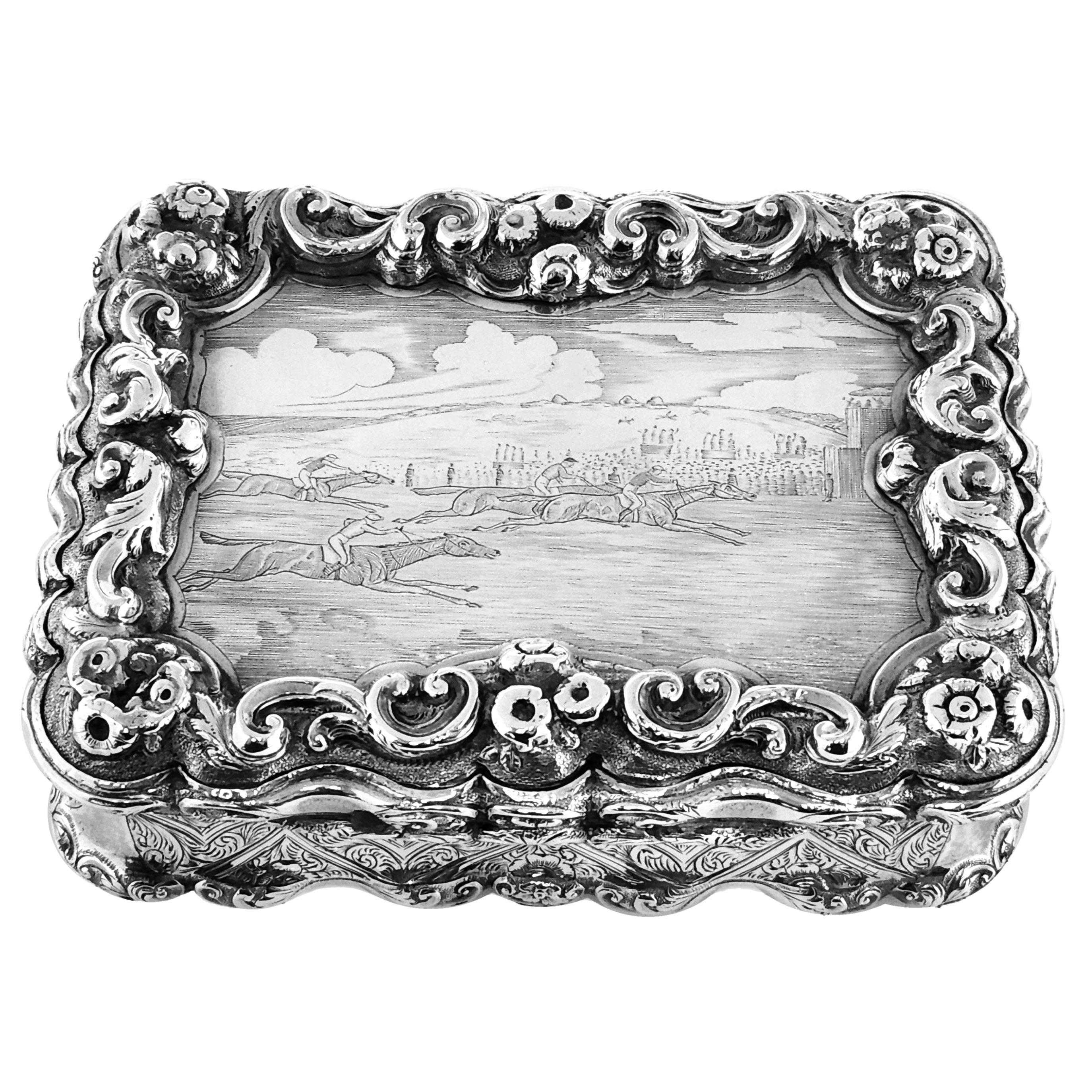 An impressive Antique Victorian solid Silver Table Snuff Box with an ornate chased border and an engraved horse racing scene on the lid. The rectangular Box has a decorative shaped border and is embellished with an engraved floral design on the