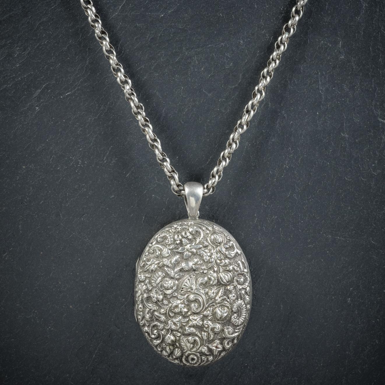 A fancy antique Silver floral Locket and chain from the Victorian era, Circa 1900. 

The large Silver locket displays beautiful embossed workmanship depicting detailed floral motifs across the front and back. 

Complete with a Silver link chain