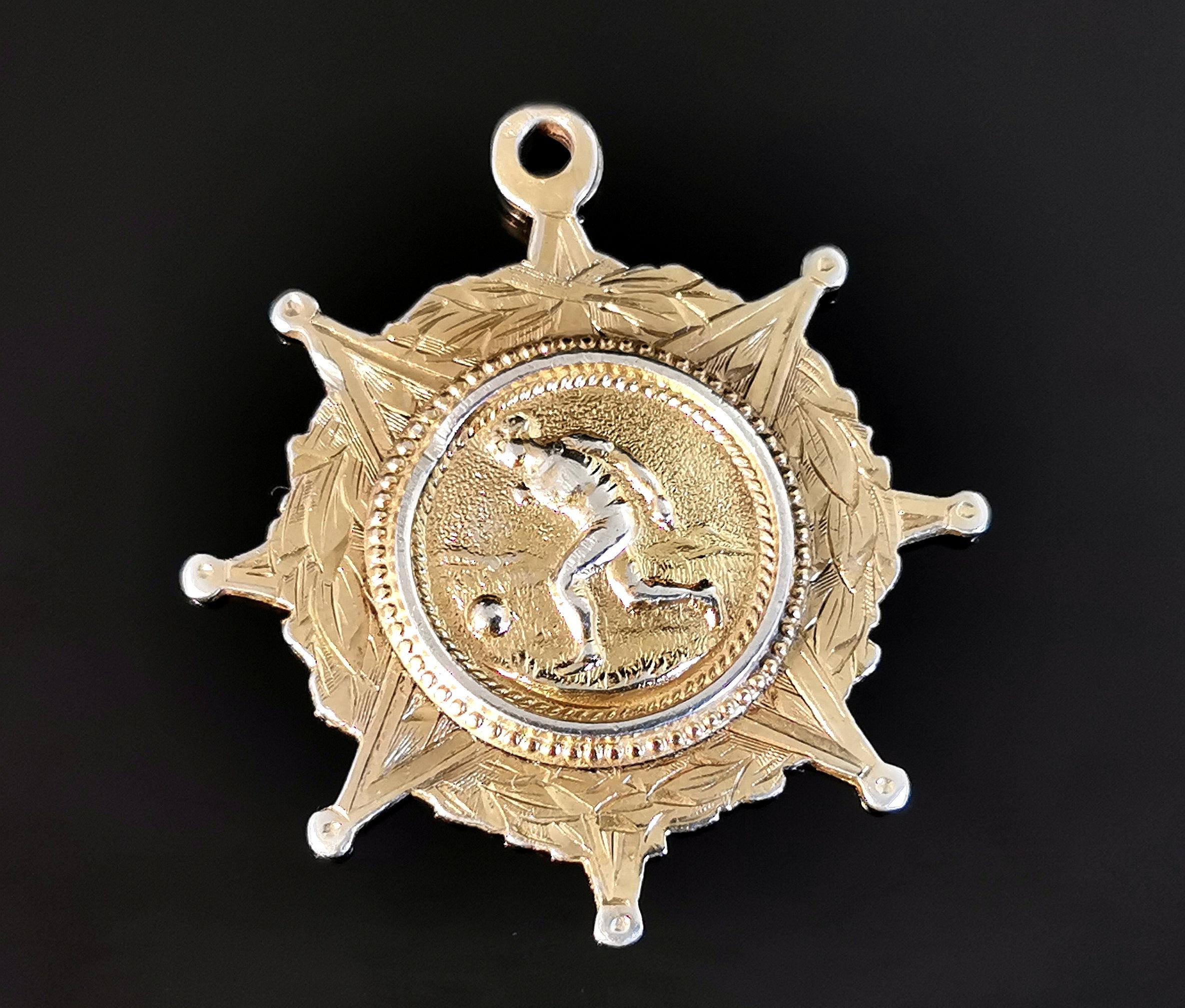 An attractive antique, Victorian gilt silver watch fob pendant.

It is a circular shaped fob with points like a star or wheel.

It is engraved with a wreath border and the centre features an embossed image of a person playing football.

The fob is