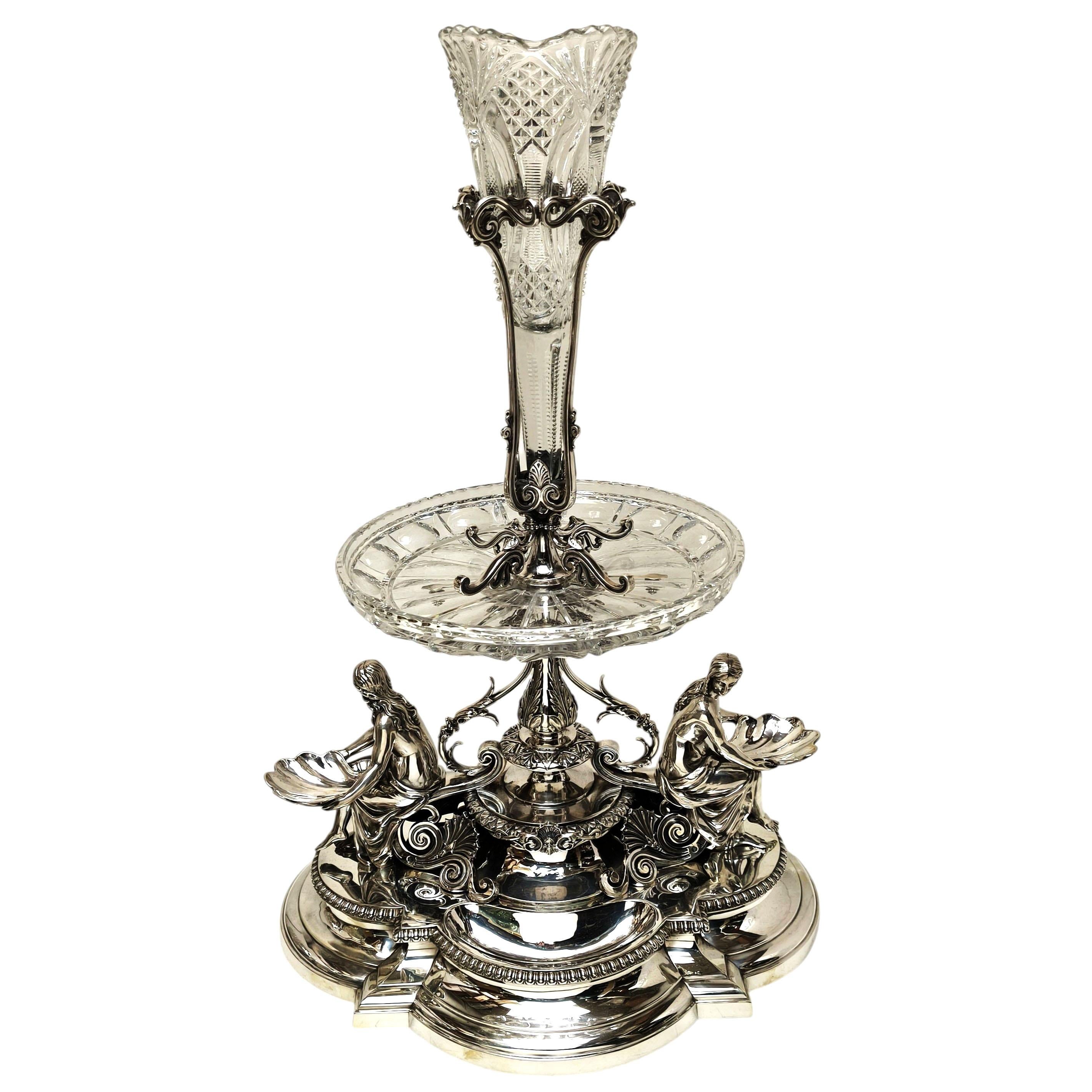 Impressionnant centre de table victorien en argent sterling et verre taillé, avec une base substantielle en forme de quadrilobe supportant une paire de vierges de style classique tenant de grands bassins en forme de coquillages tournés dans des