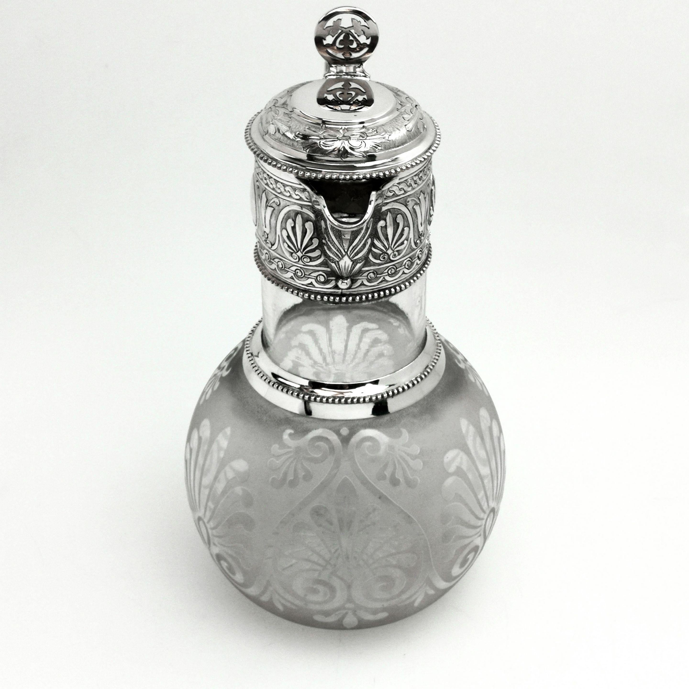An elegant Antique Victorian solid Silver mounted Claret Jug. The round body of the Jug has a decorative pattern on the glass with a frosted glass background. The silver neck and hinged lid both feature lovely chased decorative patterning. The Jug