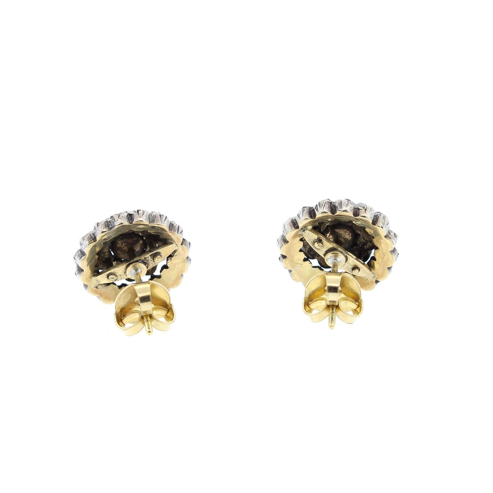 A pair of antique silver topped gold rose cut diamond cluster earrings, circa 1880. Formed as two rows of rose cut diamonds centering upon a larger rose cut. These earrings are dimensional and easy to wear. There are 54 rose cut diamonds that weigh