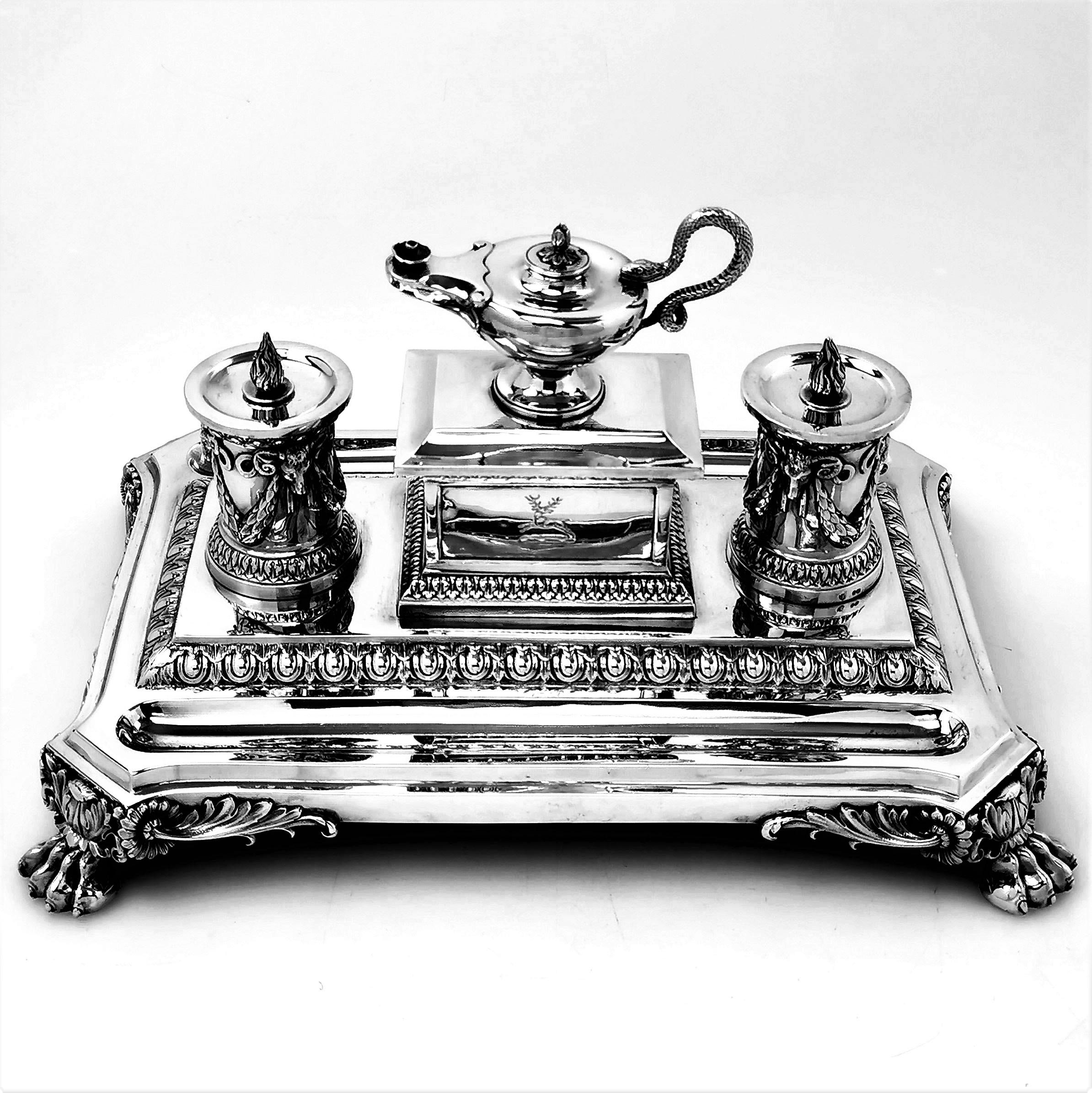 A magnificent Antique Victorian sterling Silver Inkstand with a pair of Inkwells, a central rectangular box with a fitted lid supporting a small lamp with a snake handle. The Inkstand has a rectangular base which stands on four impressive claw feet