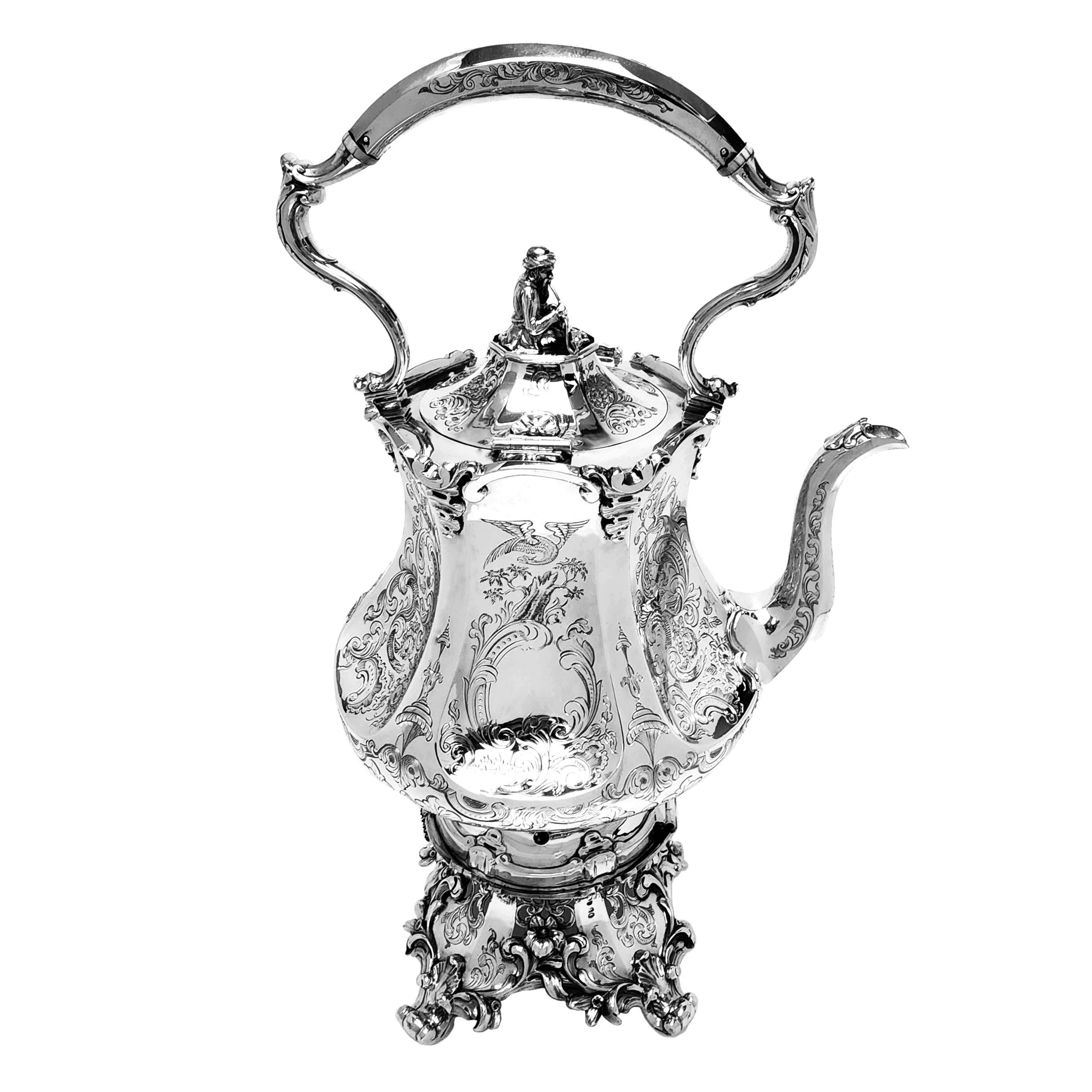 Ein prächtiger antiker viktorianischer Wasserkocher aus massivem Silber auf einem Ständer. Der Kessel hat eine zarte, facettierte Form, wobei jede Platte ein detailliertes, eingraviertes Design mit Vögeln, Schriftrollen und stilisierten Blättern und