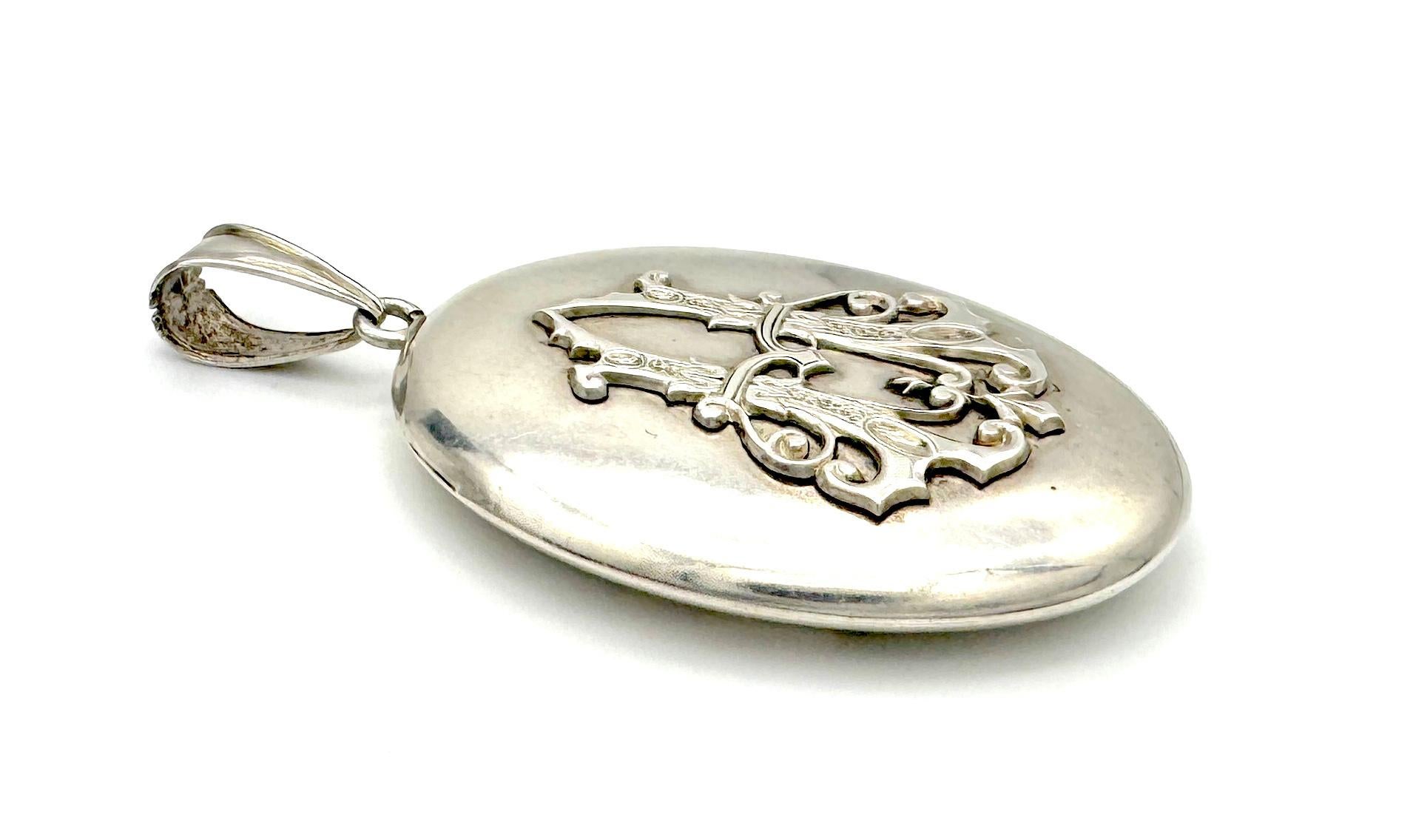 This large elegant locket was created out of silver in 1880 ca. It is decorated with a letter A in elaborate gothic script. The reverse of the locket is fitted with an oval hinged window with the original bevelled glas. The locket is in good