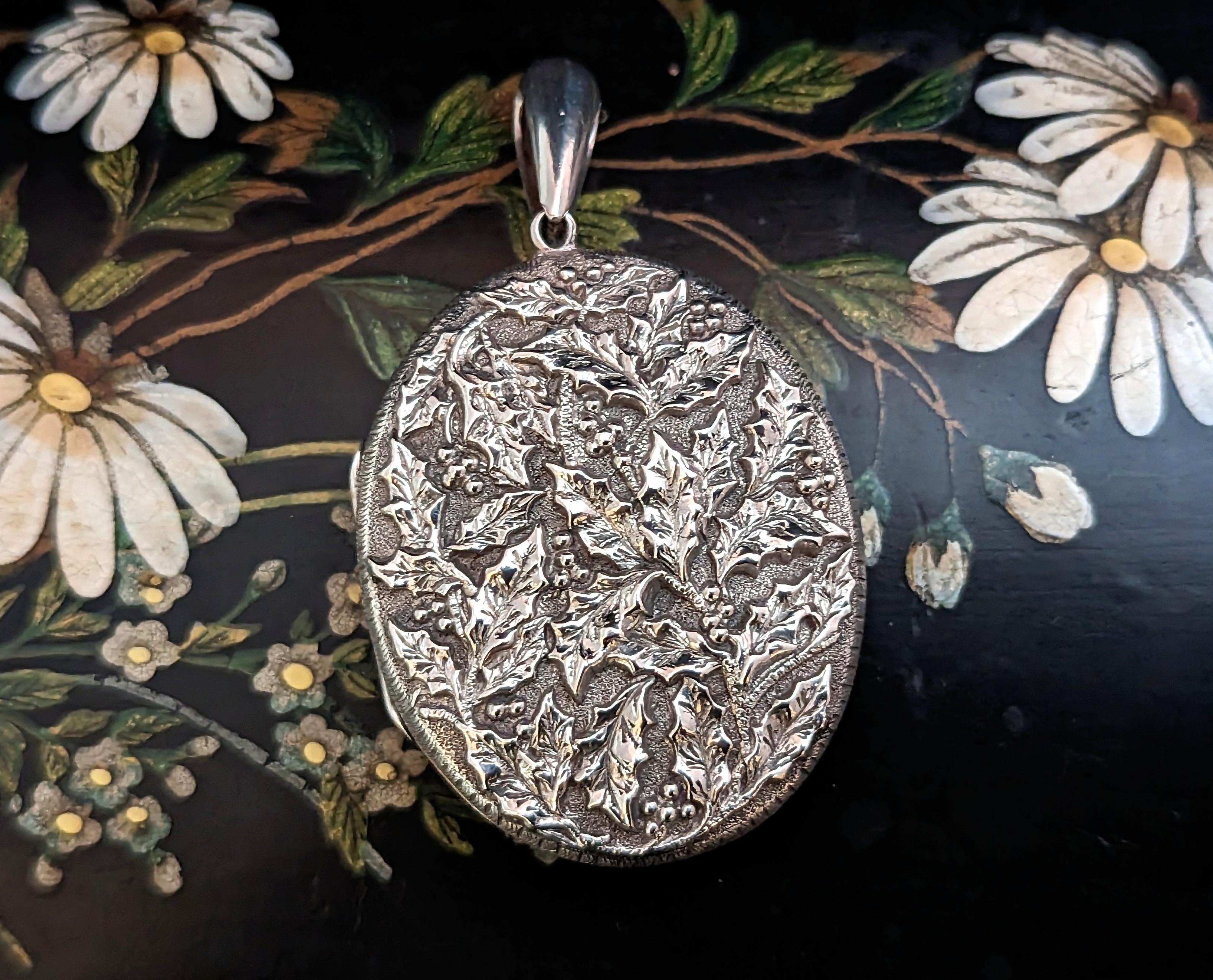 A stunning antique Victorian sterling silver locket pendant.

A large sized oval locket with a beautiful repousse design of Holly leaves and berries.

The locket has the same design front and back and is able to hold photographs or a tiny keepsake,
