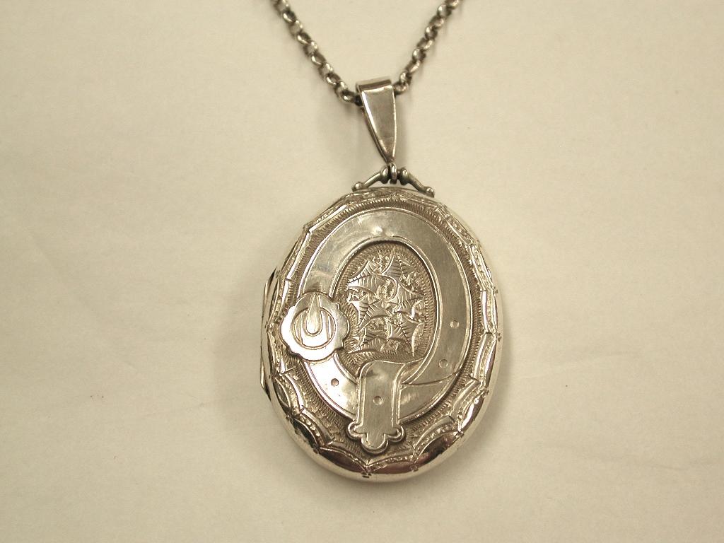 Antique Victorian Silver Locket,Birmingham, 1884 On Old Silver Belcher Chain
Typical buckle centre with ivy decoration  in the middle and victorian bright cut engraving
around the edge.