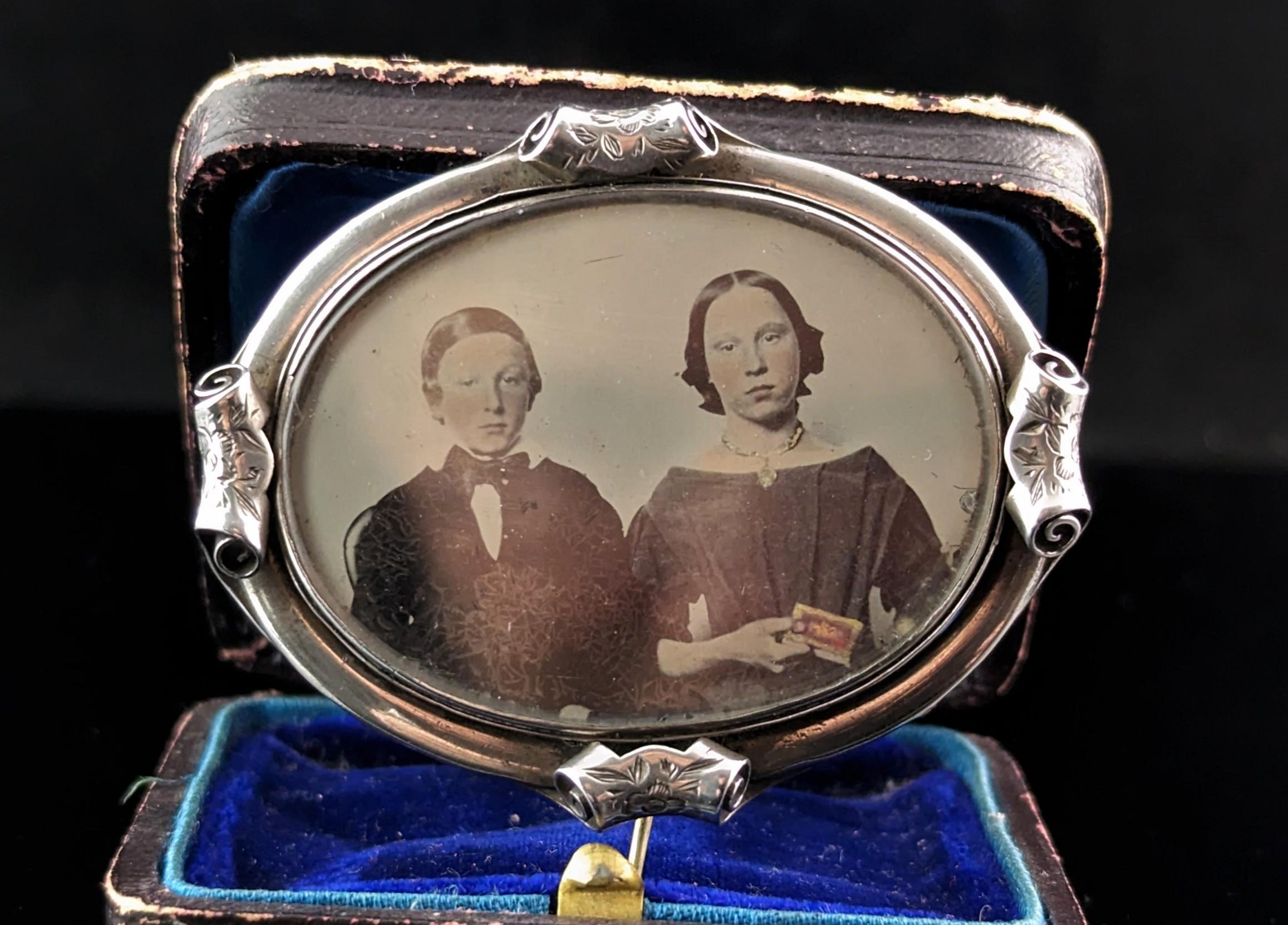 A very unusual Victorian pendant brooch.

It is a Mourning pieve and most likely contained hairwork or a hand painted portrait but now contains a melancholy hand tinted portrait of two children, probably siblings.

It has a sterling silver frame