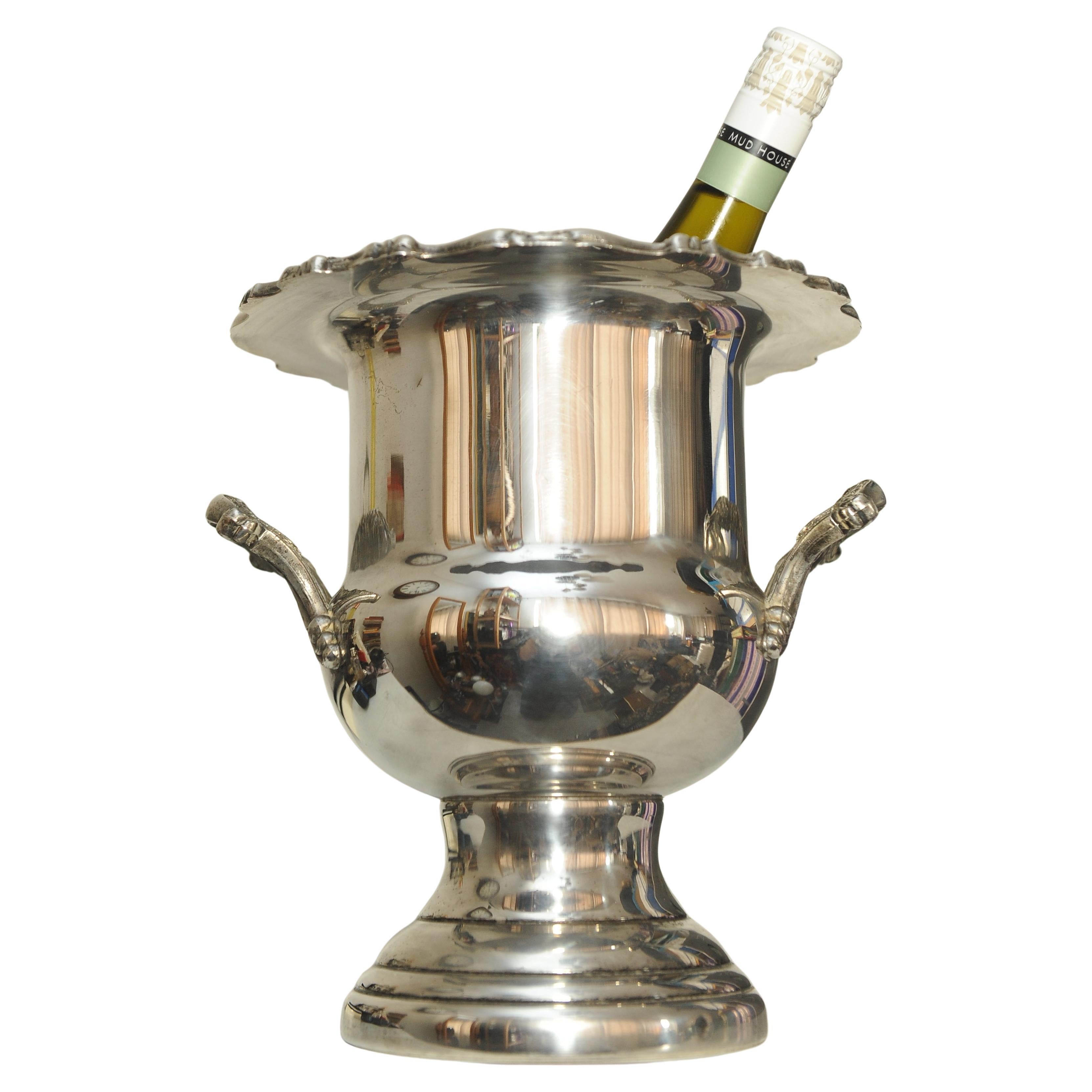 Portabotellas Campagna Antiguo Plateado Con Cuerpo De Dos Asas Y Borde Floral Desplazado 

Enfriador de champán o vino 

Altura total: 26 cm
Altura interior: 17 cm
Diámetro superior: 23 cm
Diámetro de la base:15 cm
