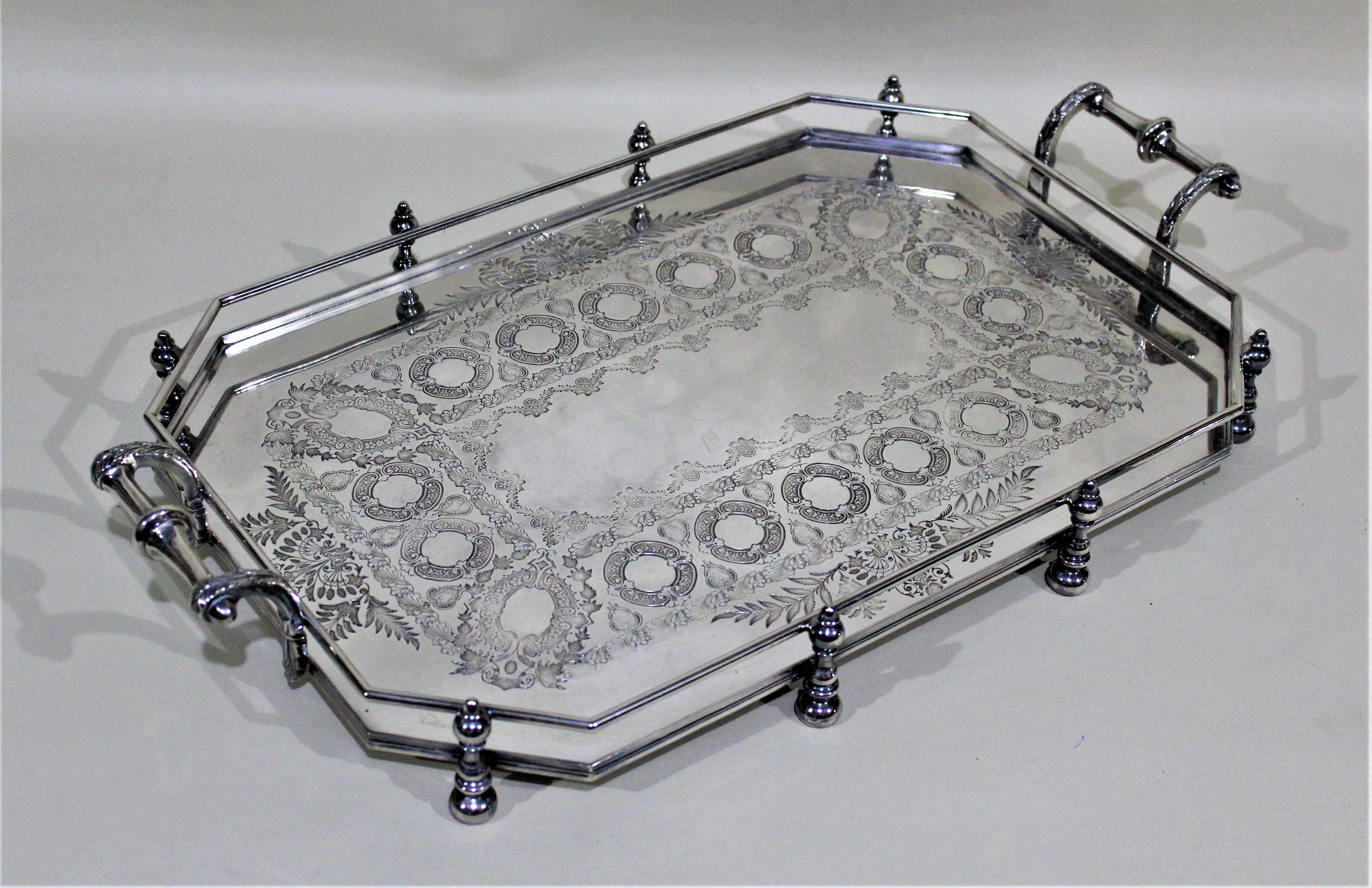 Dating from the early 20th century and made by the well known makers Walker & Ross of Sheffield England, this silver plated gallery tray has a very bold post and rail styled construction, and a highly engraved top. The bottom of each post is