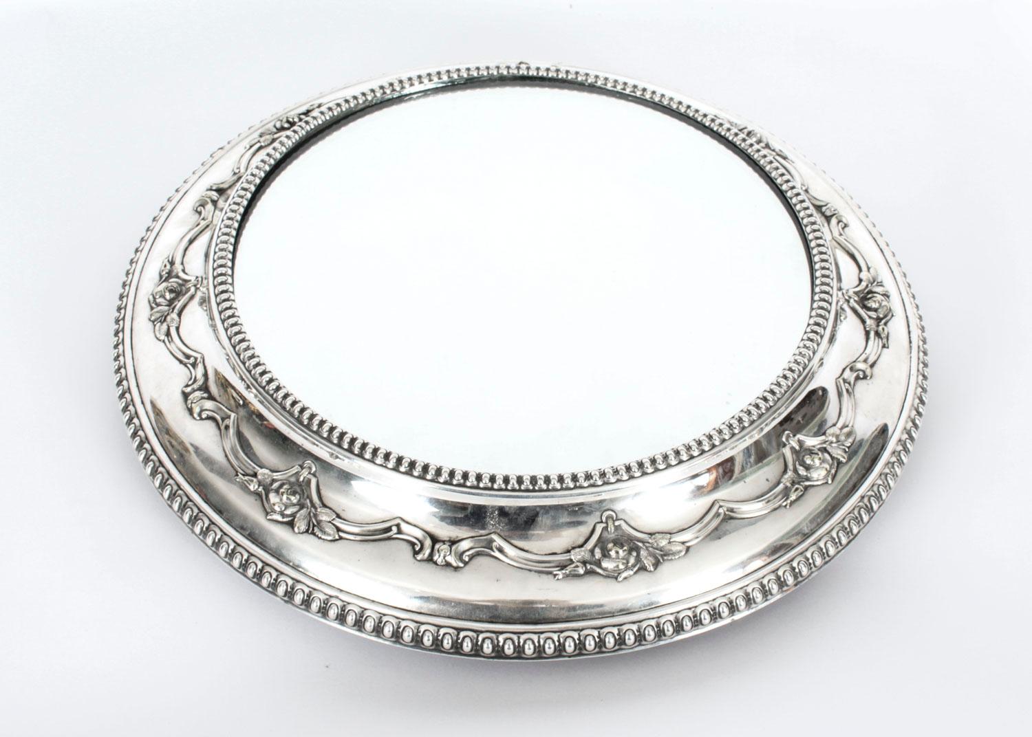 This is a large fabulous antique Victorian silver plated cake stand with the original mirrored plate Circa 1880 in date.
 
The circular stand features beaded egg and dart borders framing foliate and scroll cast decoration with a central mirrored