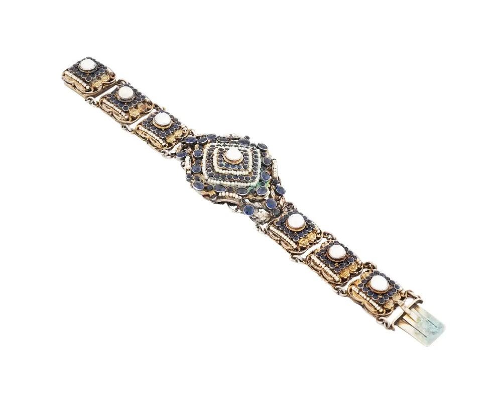 A sterling silver link bracelet with gilt accents. The large links are set with rows of faceted sapphire stones, natural pearls, The backside of the bracelet is decorated with an engraved floral ornament. The item has a box clasp. Luxury Statement