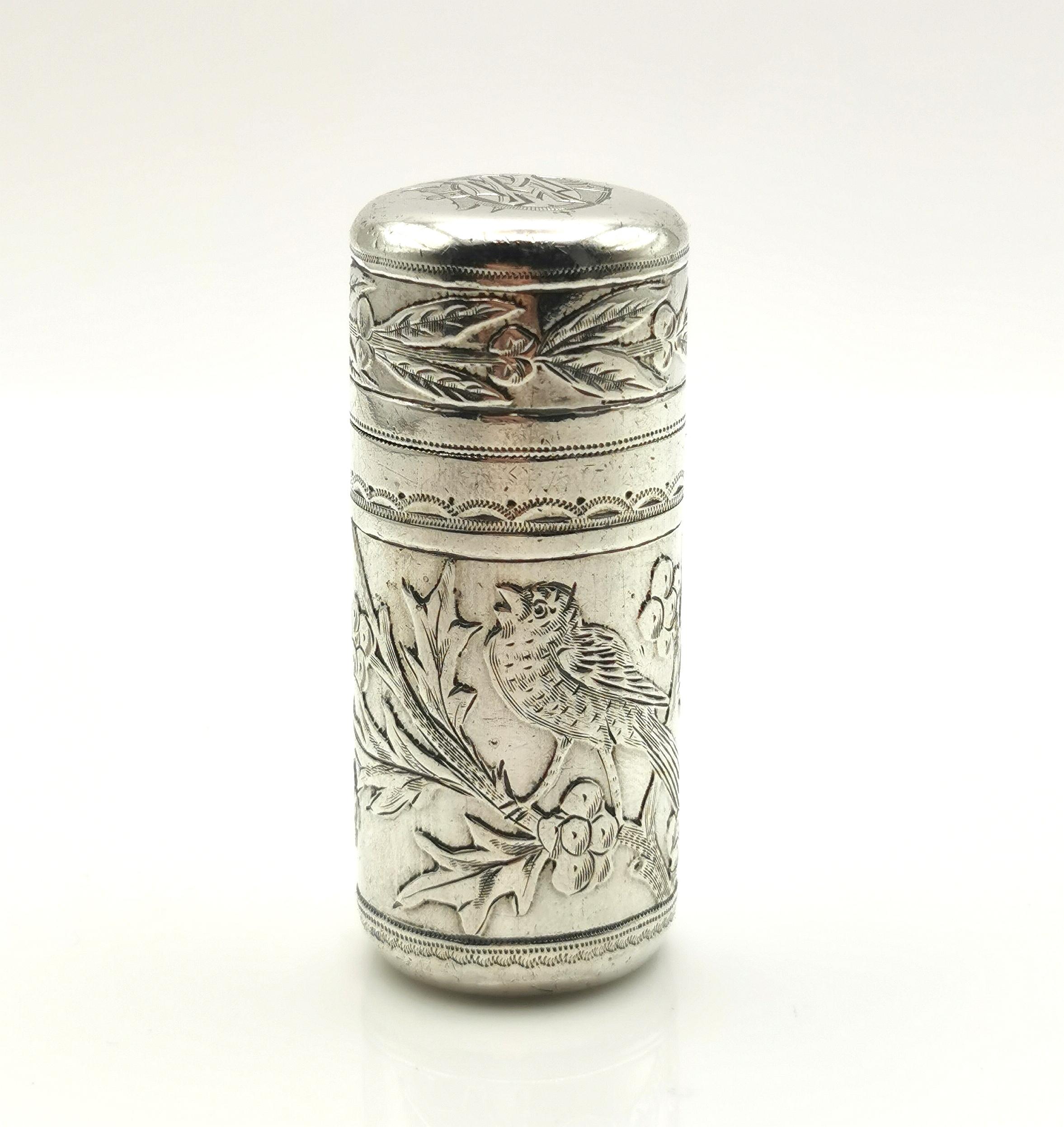A beautiful antique sterling silver scent bottle.

This is a cylindrical scent bottle made from sterling silver with a glass liner and stopper.

It has the prettiest engraving of birds and Holly with some repousse detailing and a monogram to the lid