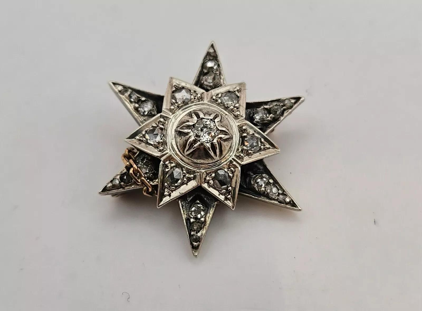 Broche antiguo, engastado en plata, broche de estrella de diamantes talla antigua con un pequeño alfiler de oro amarillo a un enganche de gancho y pequeña cadena de seguridad de broche de oro ajustada. Un diamante central engastado en ilusión de