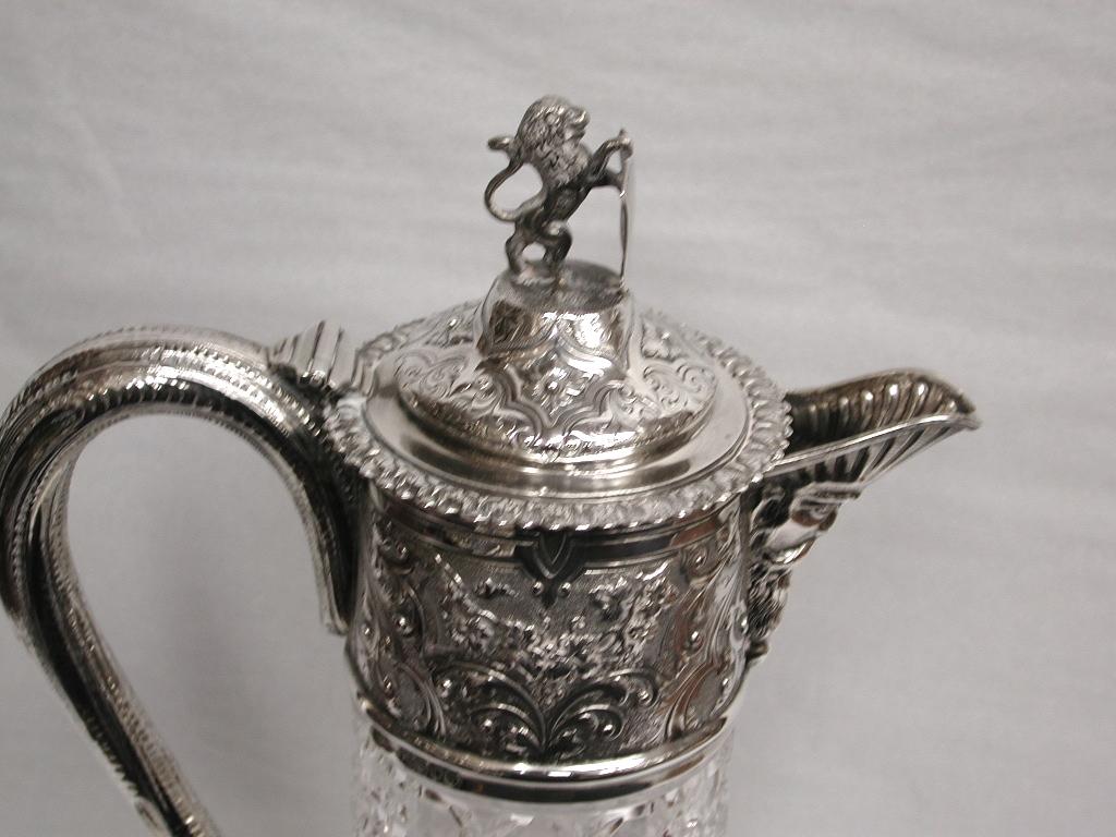 Antique Victorian silver topped cut glass claret jug, dated 1878, Charles Boyton.
Beautifully embossed silver top with grape and vine leaf and scrollwork, Bacchus faced pouring lip, with a
vine branch shaped handle and a Lion and shield on the