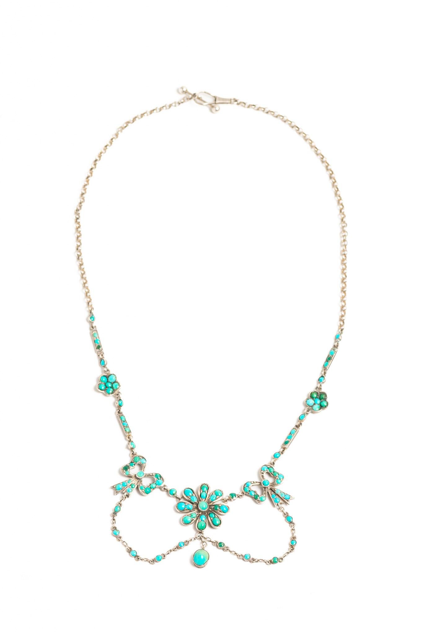 Bellissima collana antica vittoriana in argento sterling con fiori e fiocchi decorati con cabochon di turchese blu e verde. Questo pezzo vittoriano presenta un motivo floreale centrale con una deliziosa goccia turchese, due fiocchi su ciascun lato e