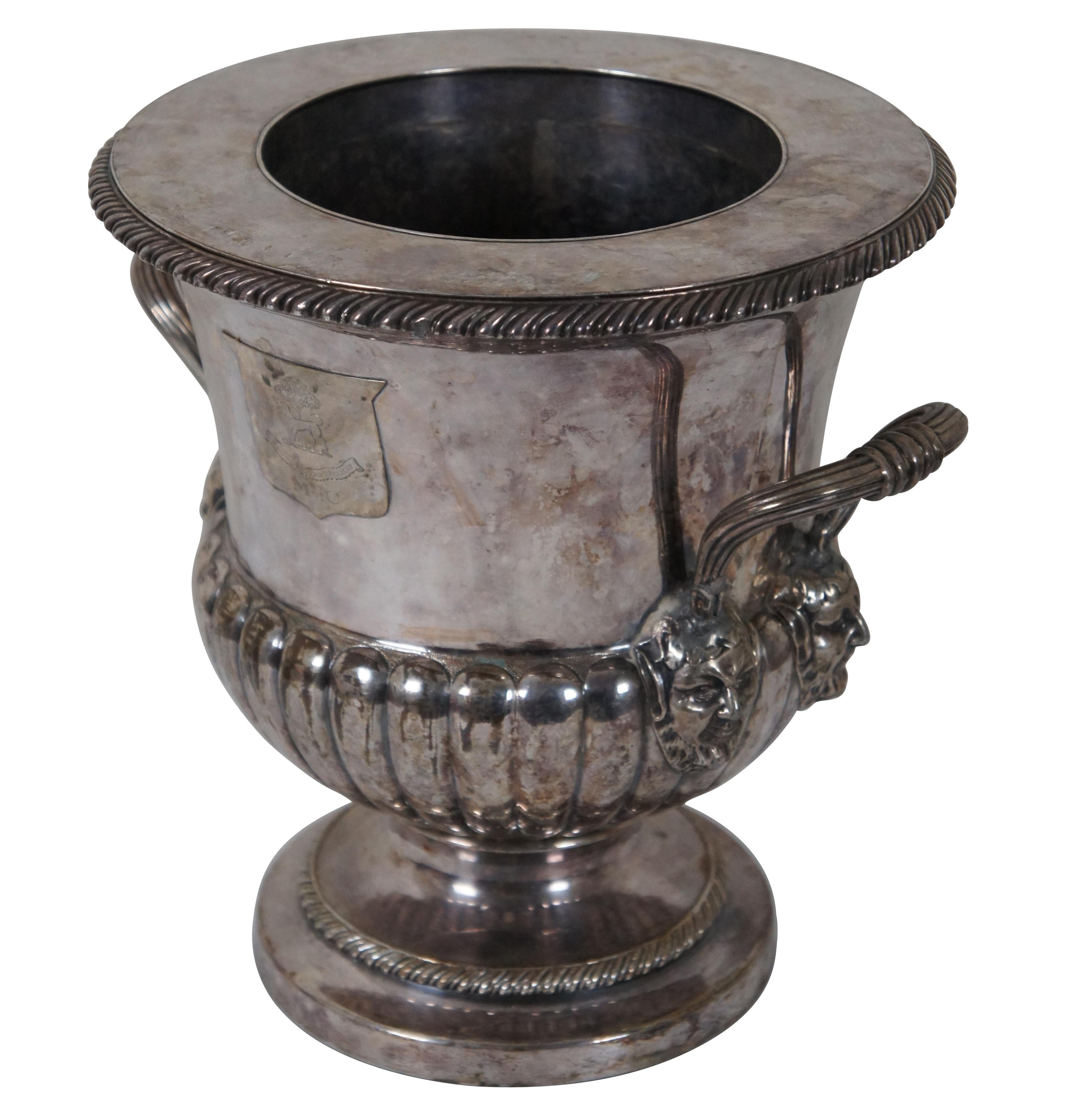 Antique silverplate champagne or wine cooler. Features classic trophy urn form with chased gadrooning throughout. Handled along each side with figural busts of Dionysis or Bacchus the god of grape harvest and wine making. Along the front is a