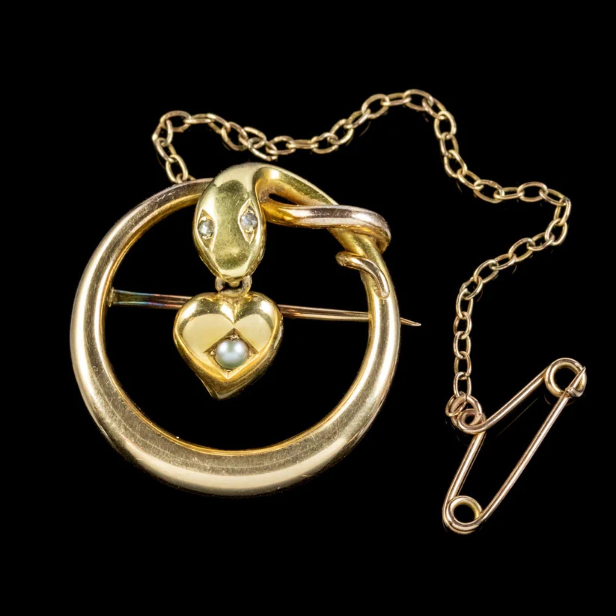 Une fabuleuse broche serpent victorienne ancienne représentant un serpent en or jaune 15ct avec des yeux scintillants en diamant taillé en rose et un cœur de sorcière suspendu à sa bouche avec une perle au centre.

Les bijoux en forme de serpent
