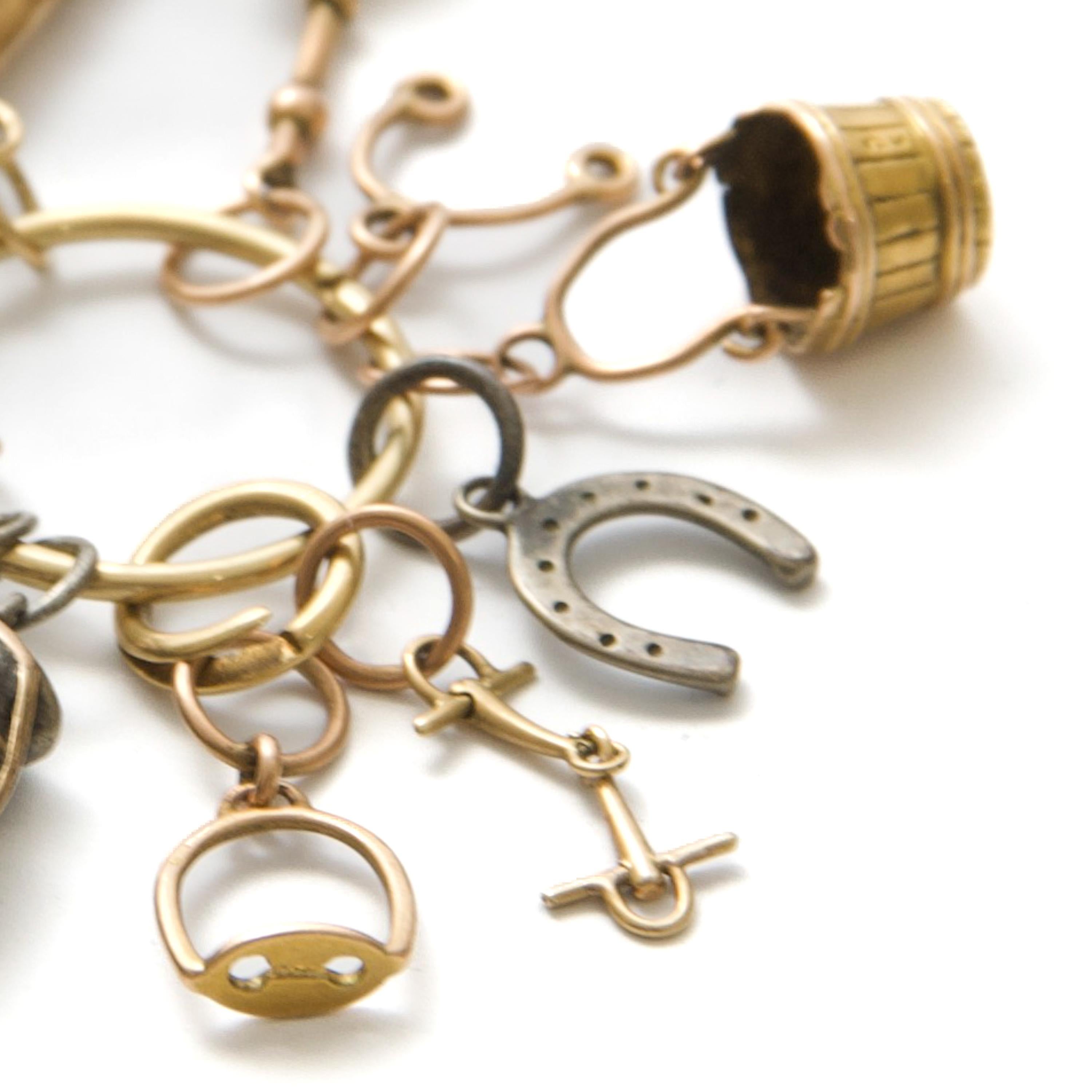 Questo affascinante pezzo equestre vittoriano è una rara e squisita collezione di charme in argento e oro, ciascuno meticolosamente realizzato per rappresentare elementi essenziali per l'equitazione. Questi charme individuali sono sospesi da un